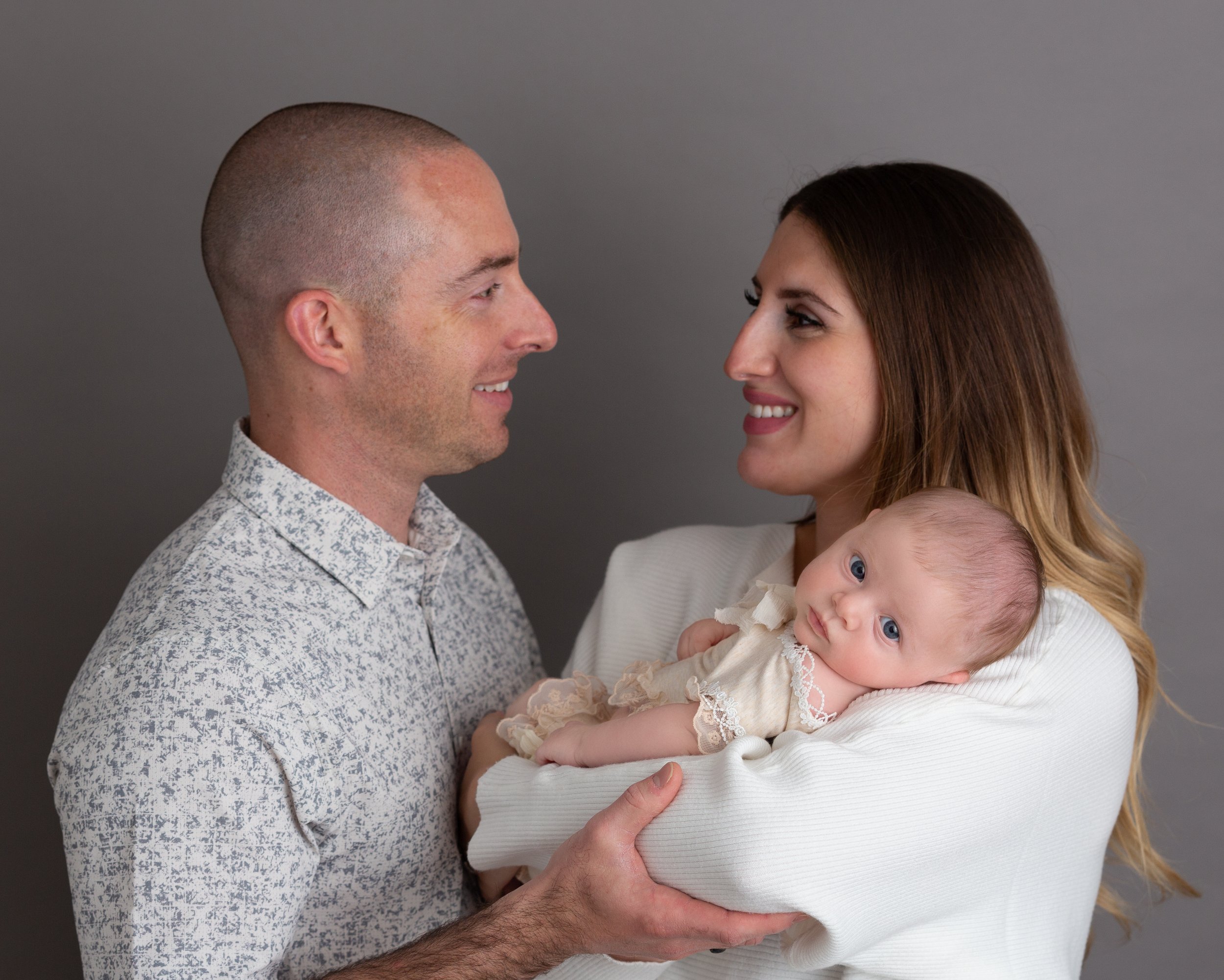 family portrait of parents looking at each other and baby looking at camera