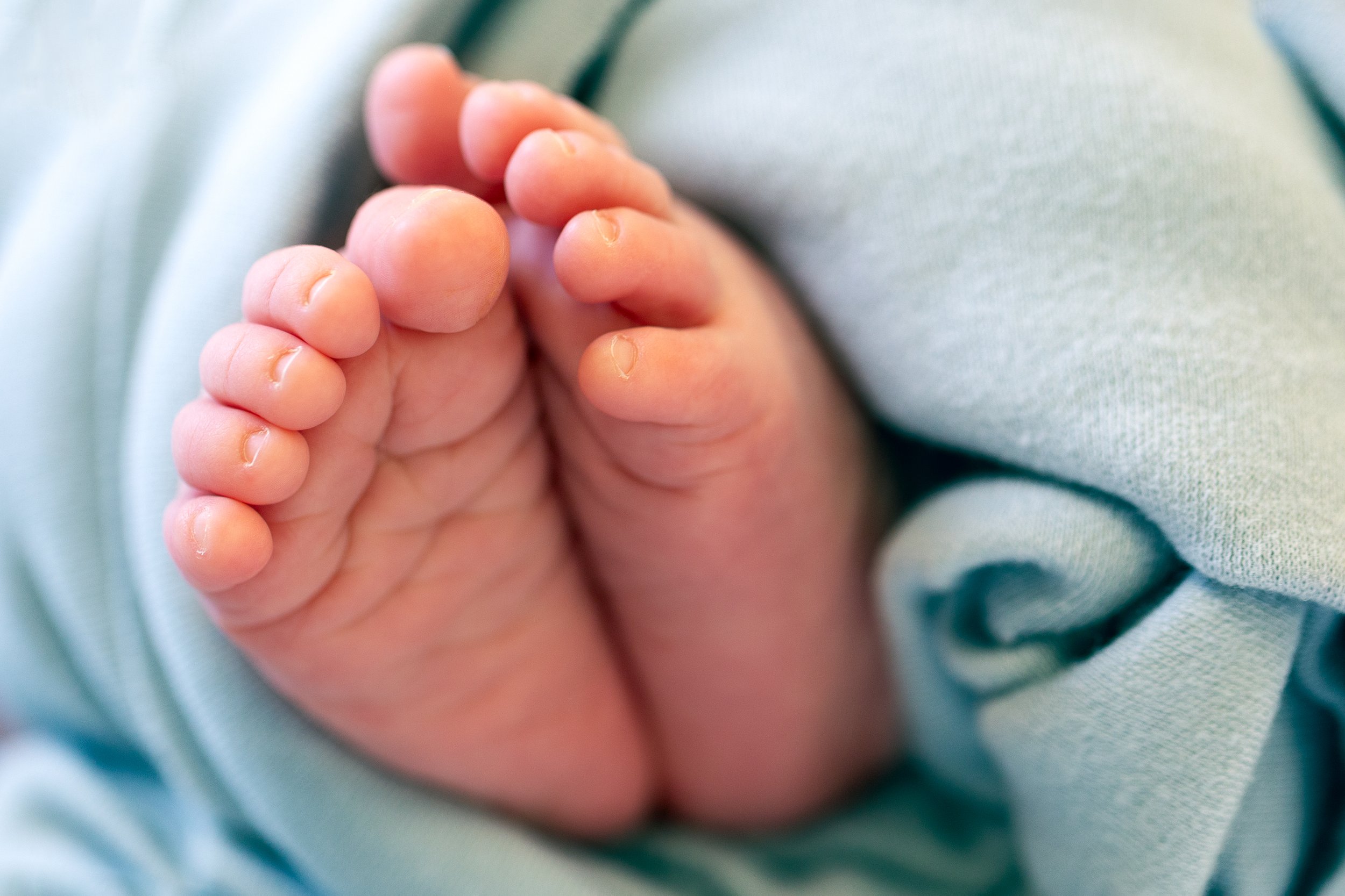 tiny newborn baby feet with curled toes