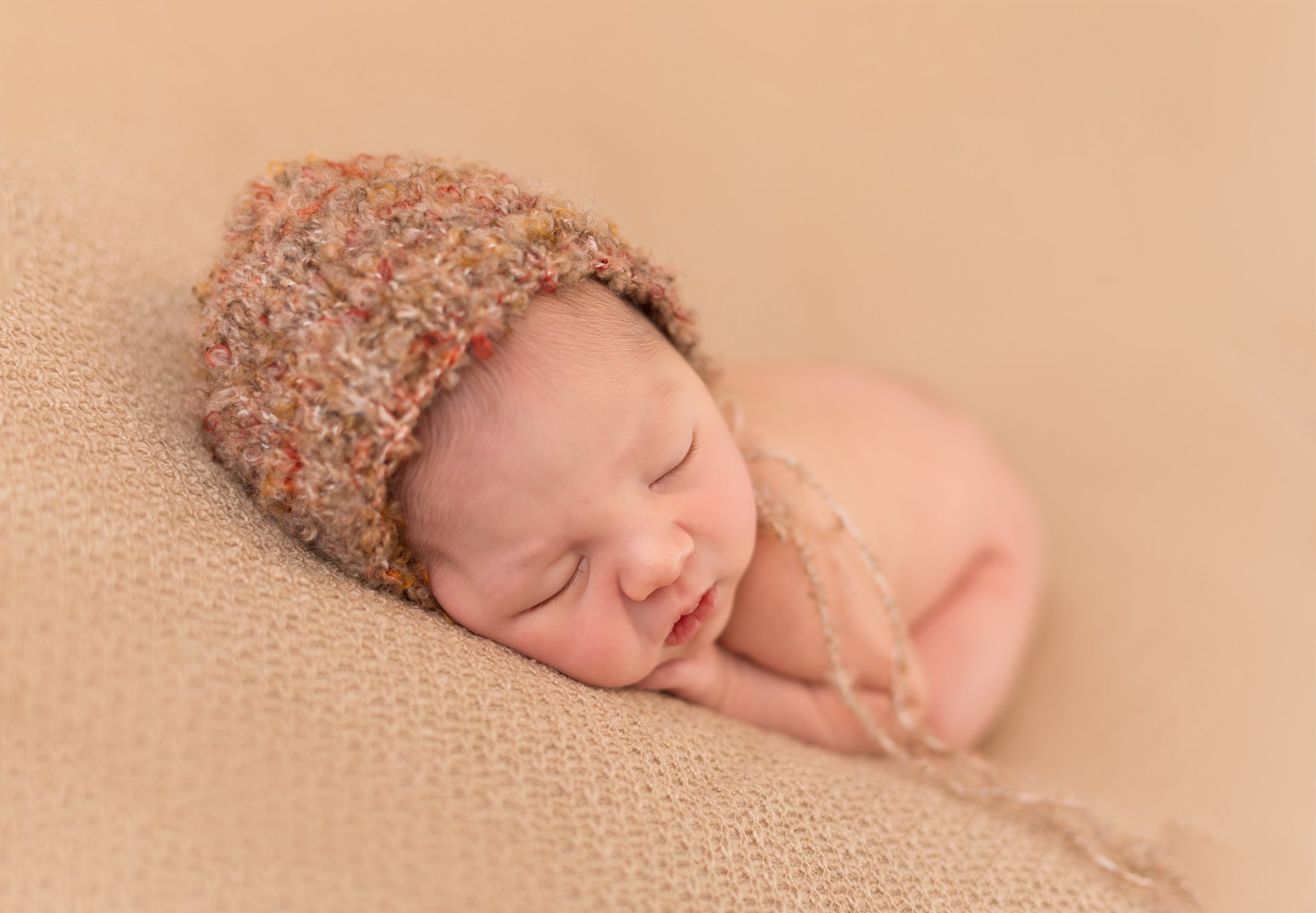 posed newborn in autumn coloured bonnet