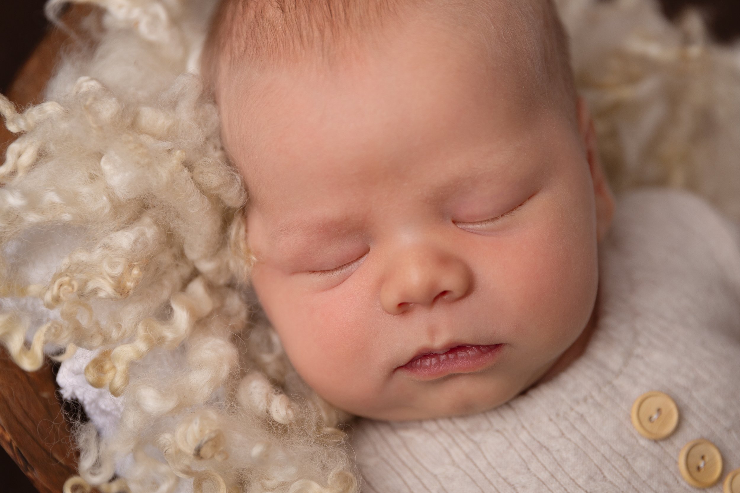 newborn boy sleeping on curly wool layer in basket