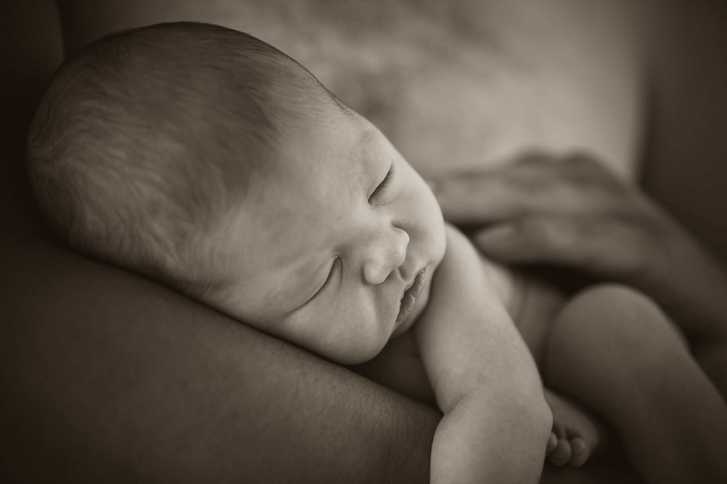 black and white picture of newborn in daddys arms
