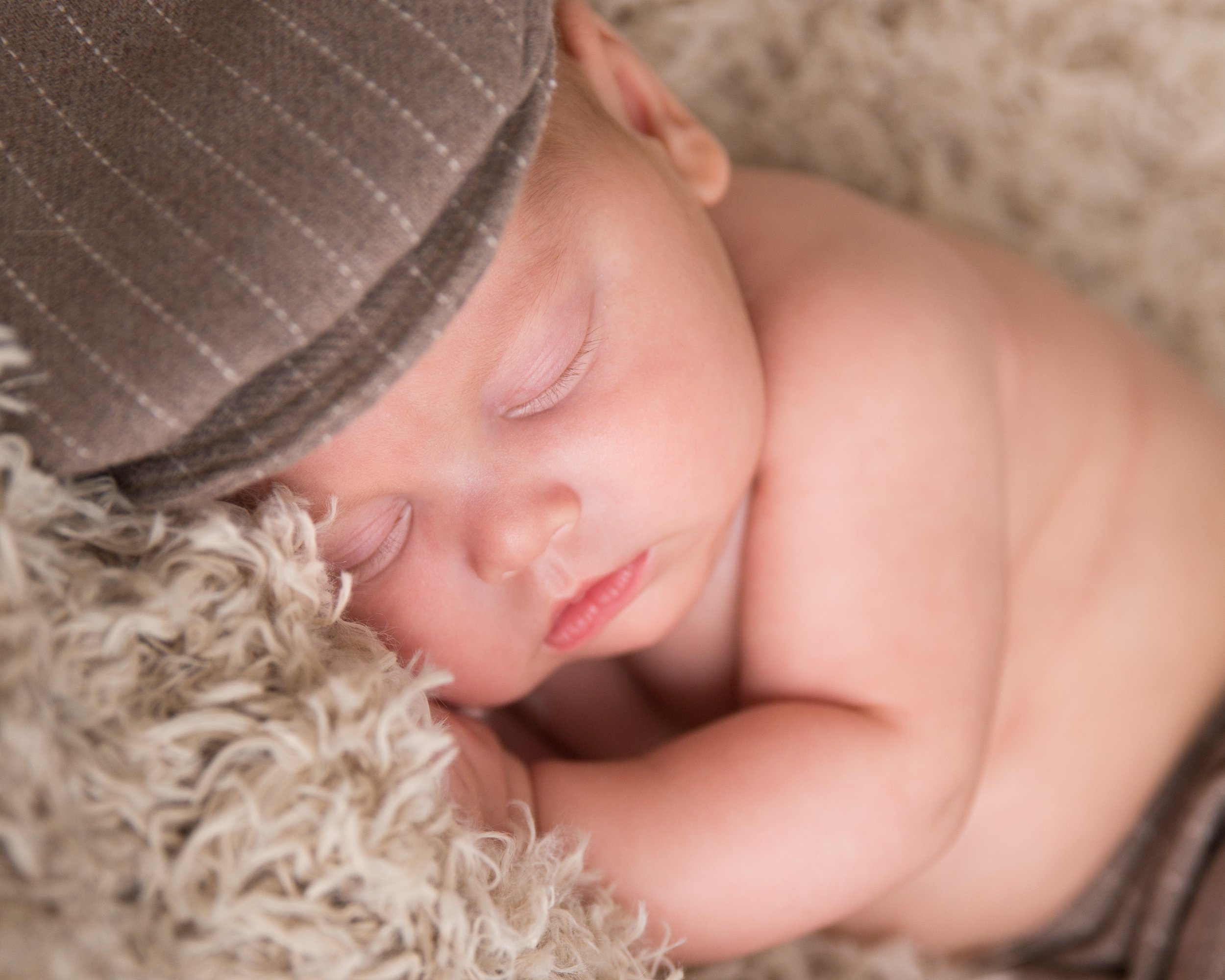 baby boy in page boy hat posed on flokati