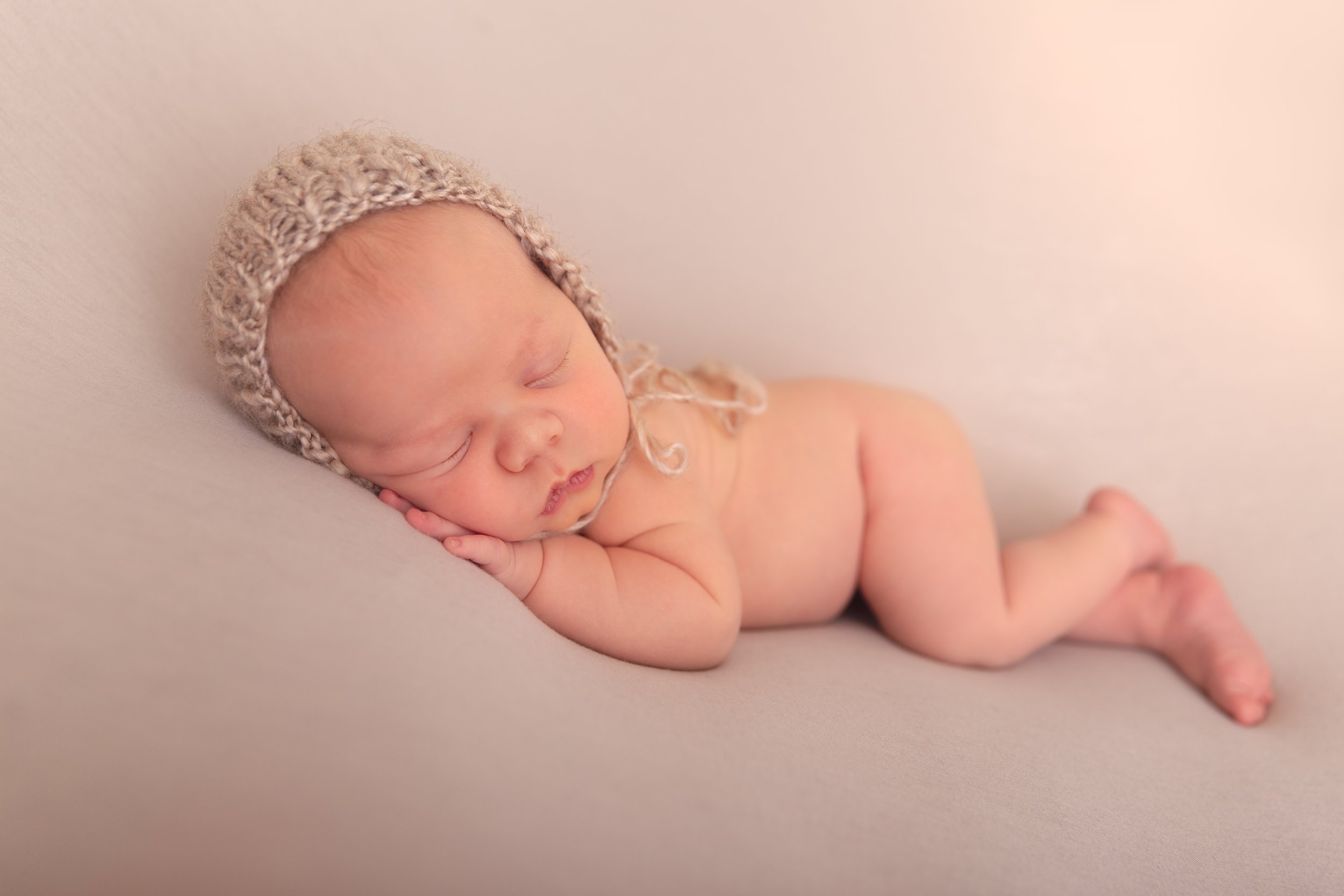 side laying posed newborn baby boy with bonnet