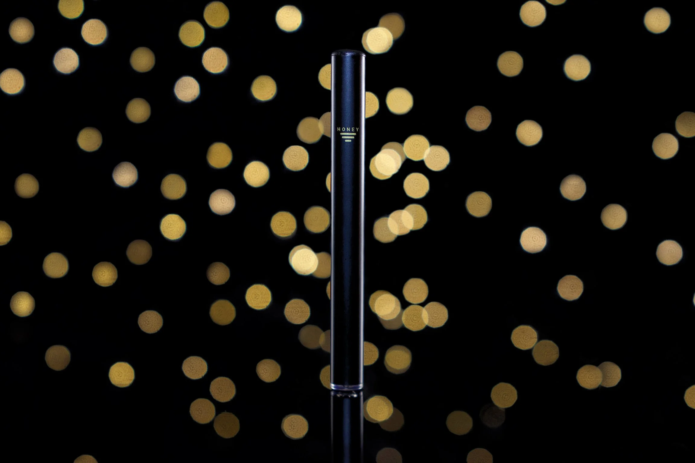 Luxury cannabis vape product photography in California with black background and golden bokeh