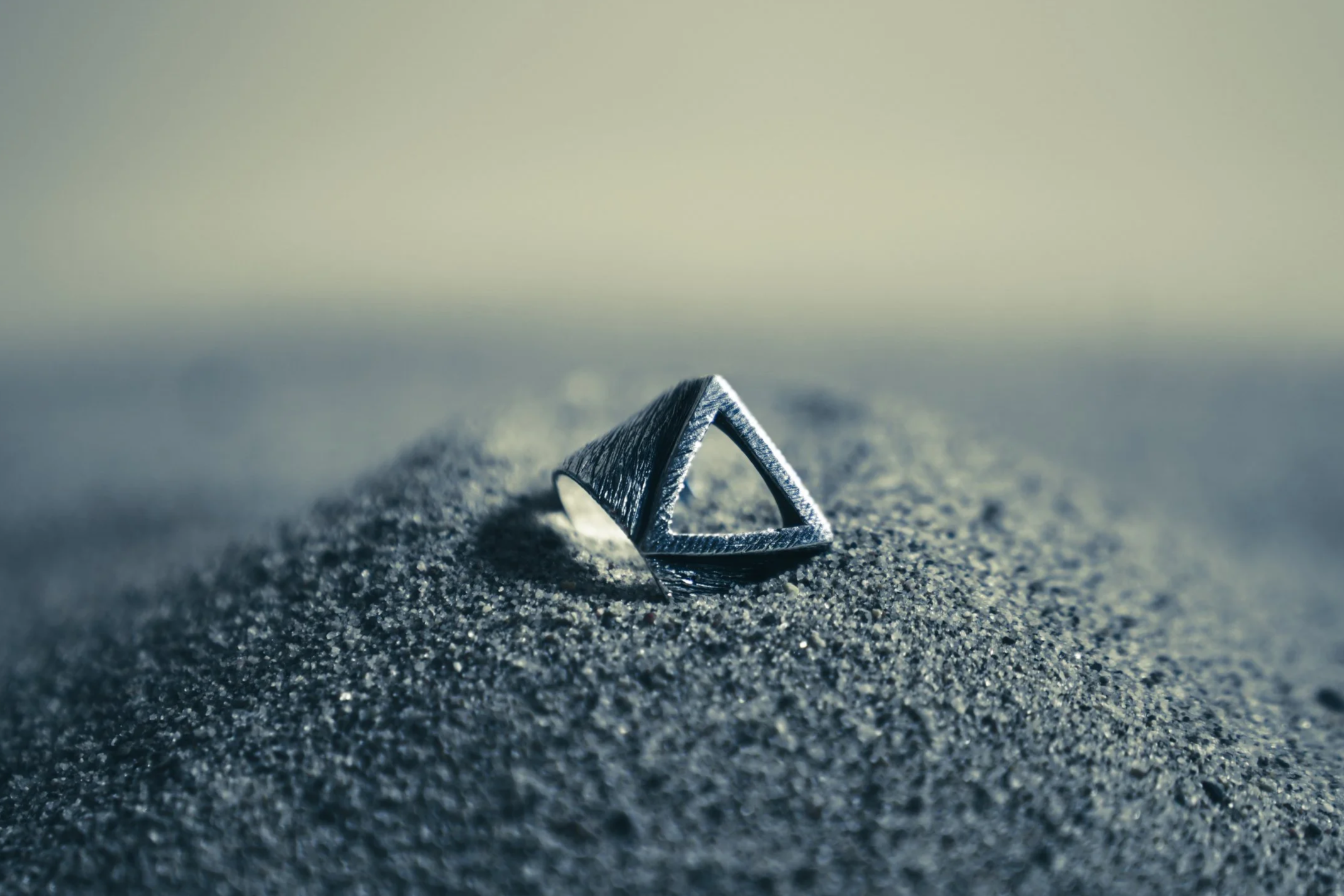 Men’s silver ring photographed on dark sand at Venice Beach, Los Angeles