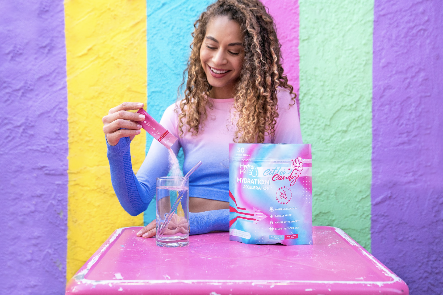 Woman holding Candy electrolyte drink pack colorful wall — wellness lifestyle product photographer Los Angeles