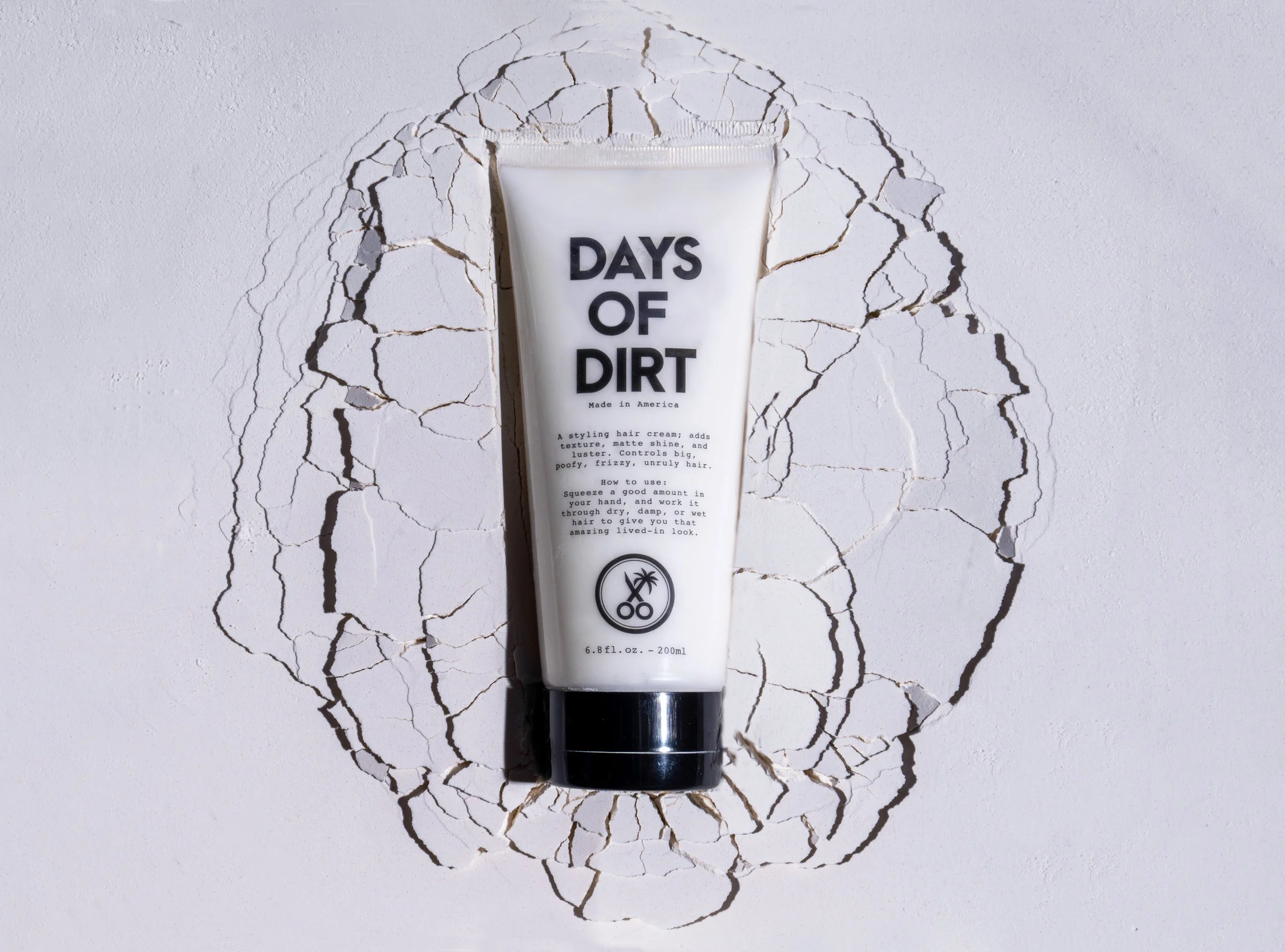 Days of Dirt men’s hair cream tube photographed on a cracked white textured surface