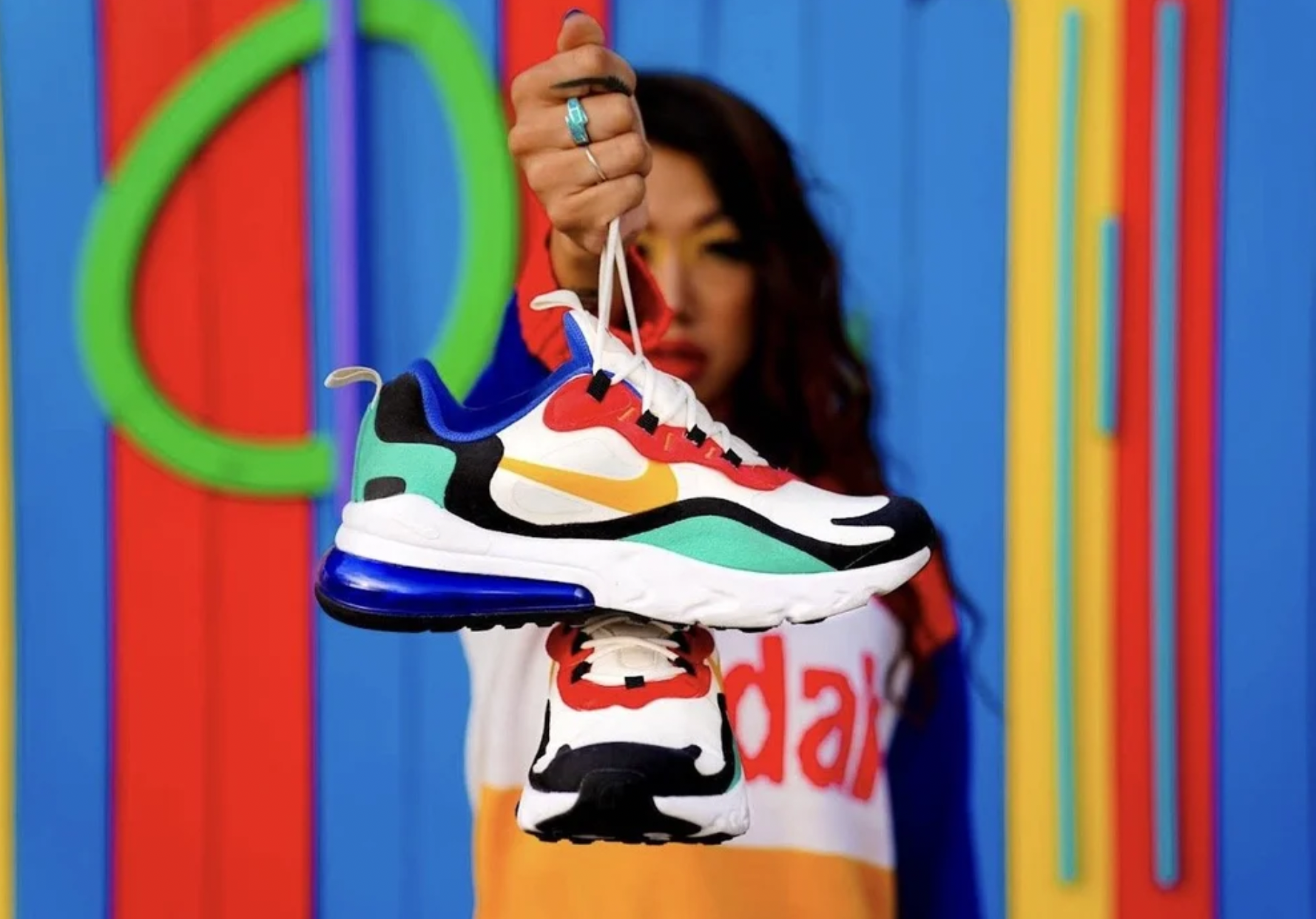 Colorful Nike Air Max sneaker held up against a bold color-blocked backdrop, a lifestyle product shot that shows the shoe's shape, sole and color story in a social-ready, in-the-moment frame