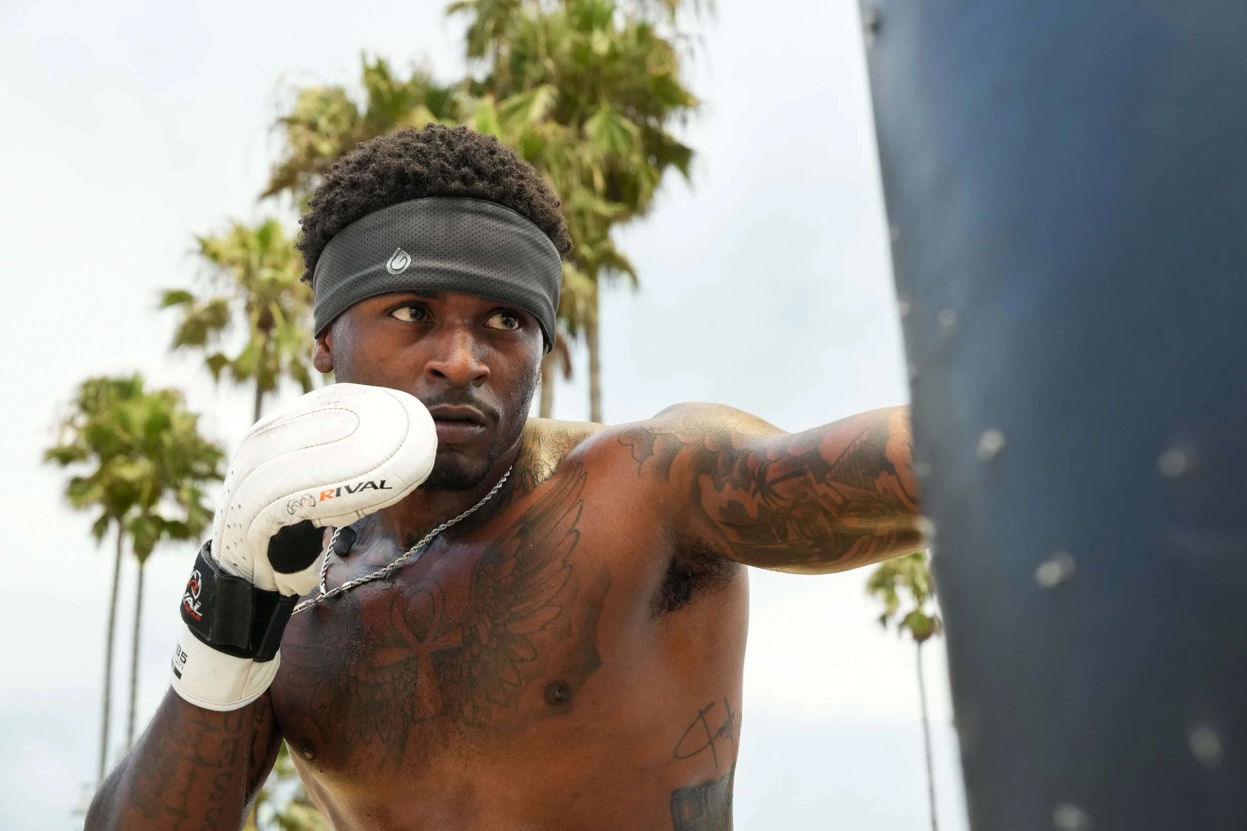 Gymwrap performance headband photographed on a male boxer beside a heavy bag, with crisp directional light revealing fit, coverage and fabric detail during active movement