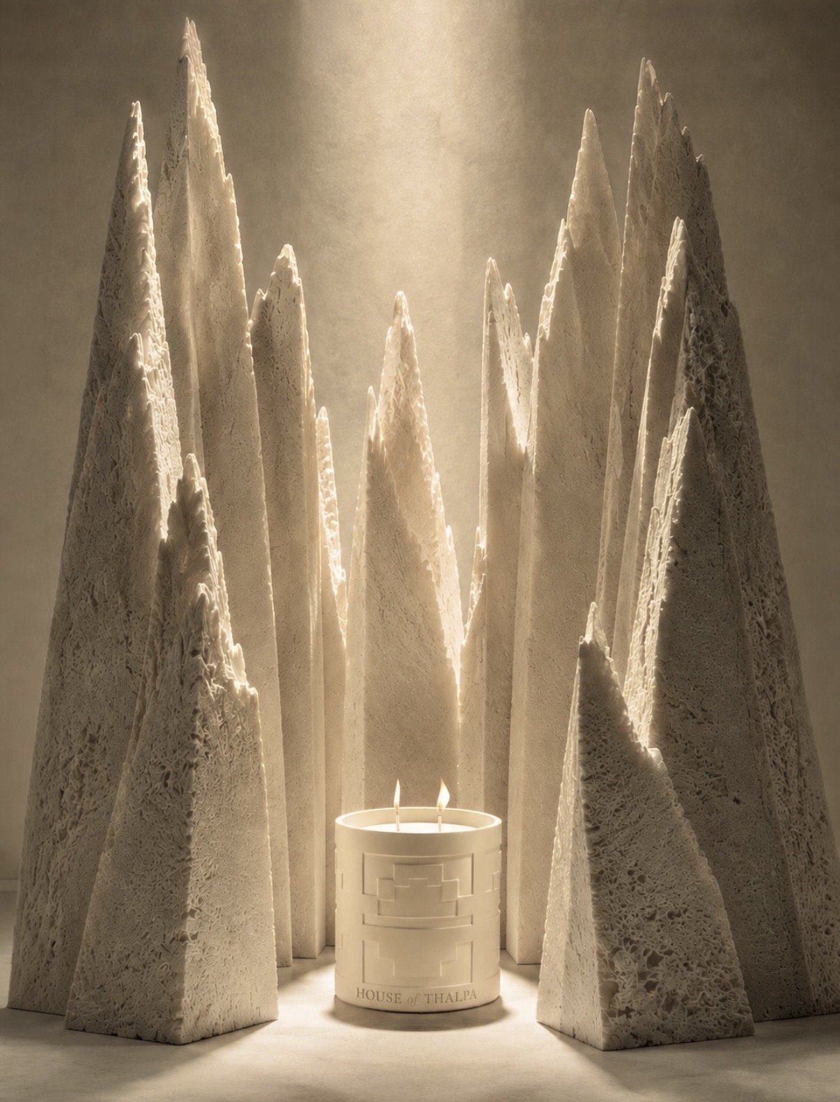 House of Thalpa candle photographed among sculptural stone forms in warm atmospheric light