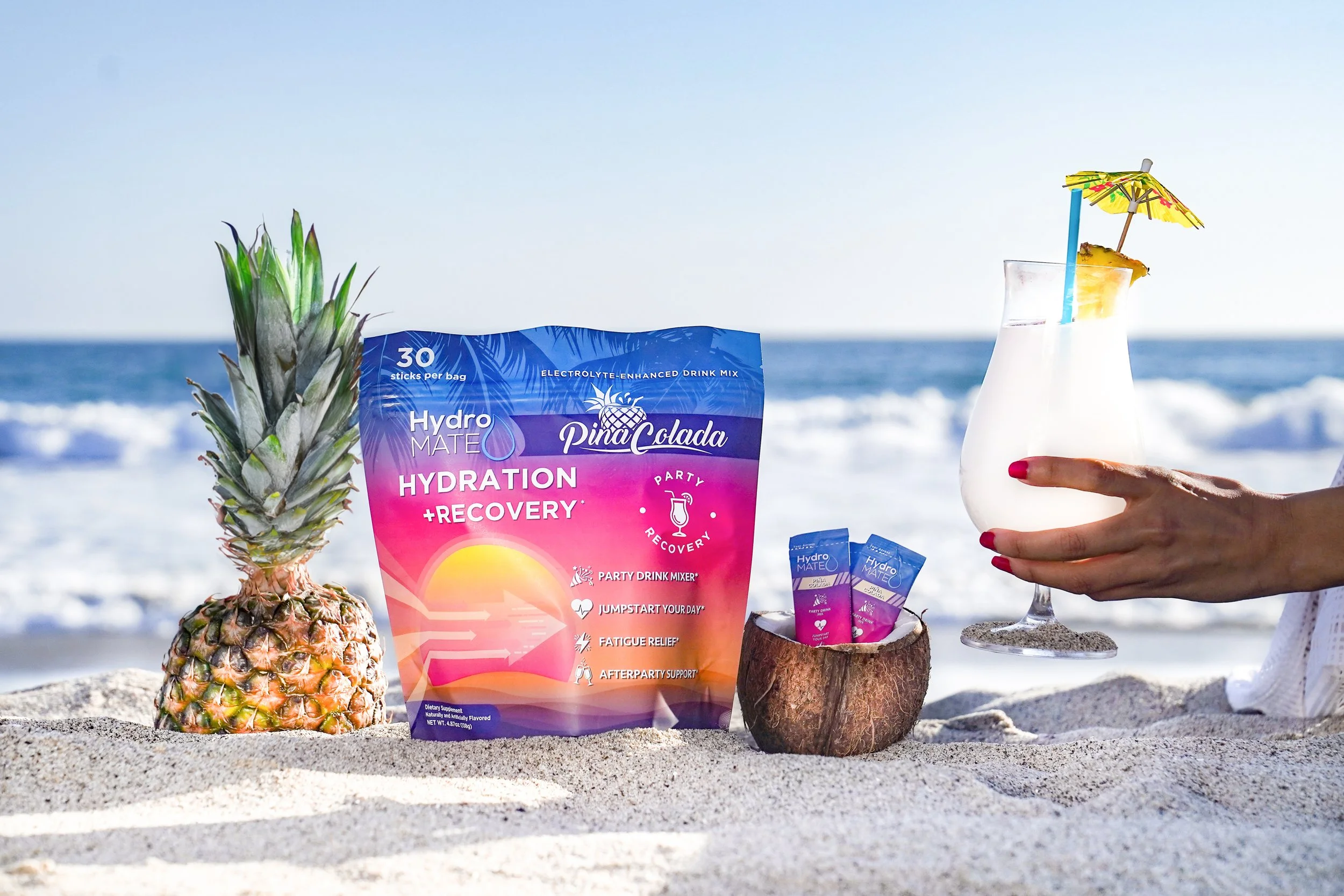 HydroMate Piña Colada hydration and recovery drink mix photographed on a California beach by Chris Frara Studios, Los Angeles product photographer