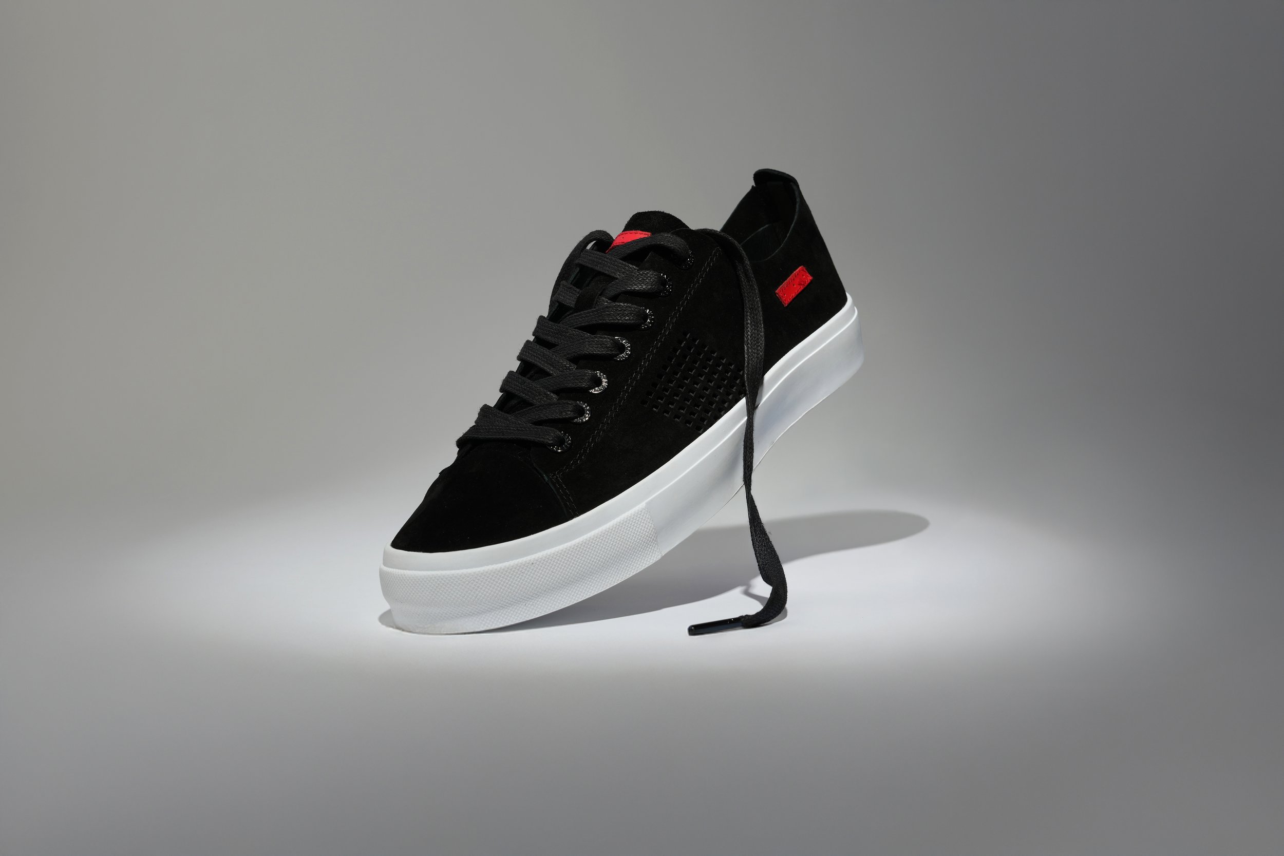 Ecommerce product photography, black sneaker on stand clean studio lighting