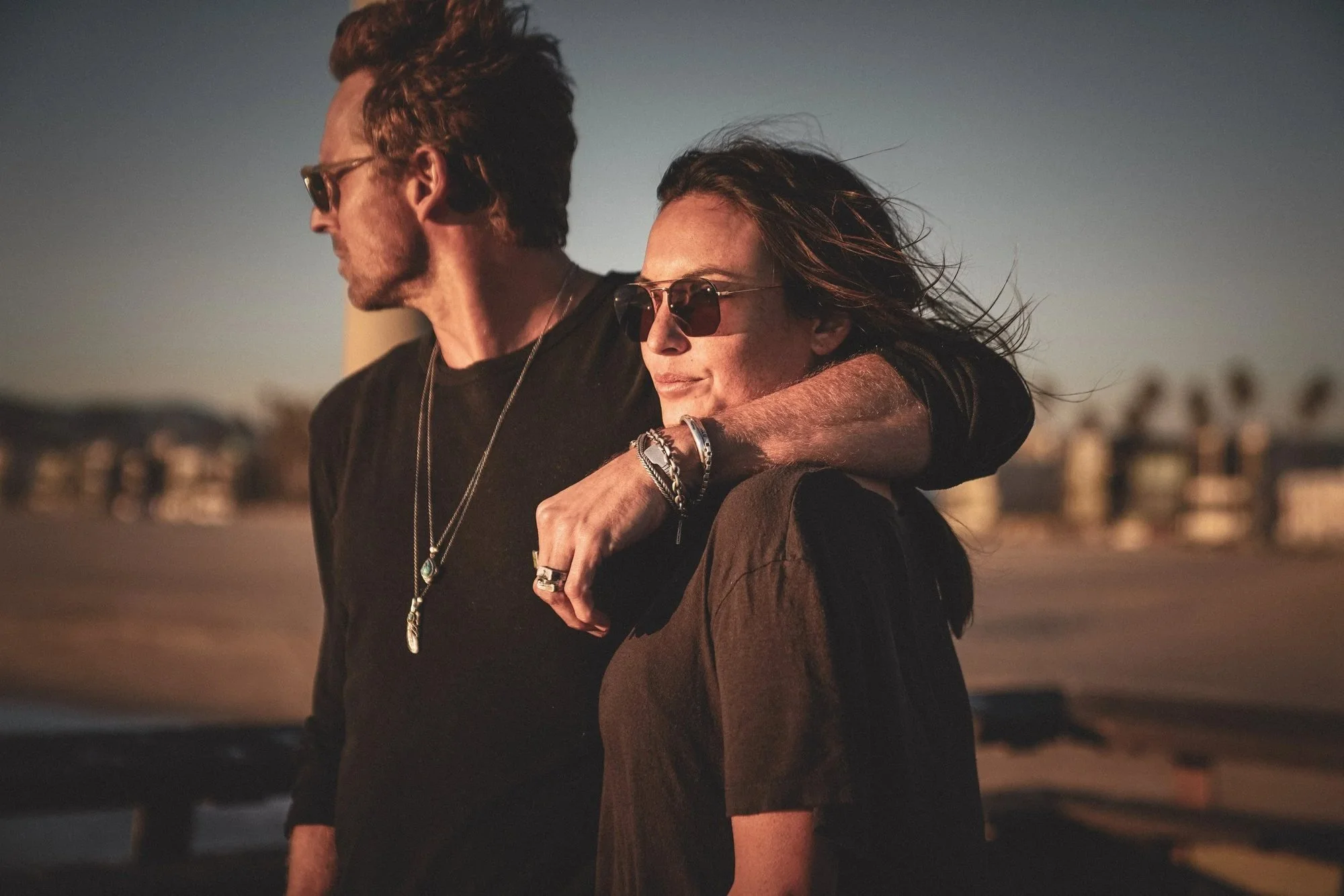 Couple embracing at the beach at sunset wearing silver jewelry, lifestyle brand campaign