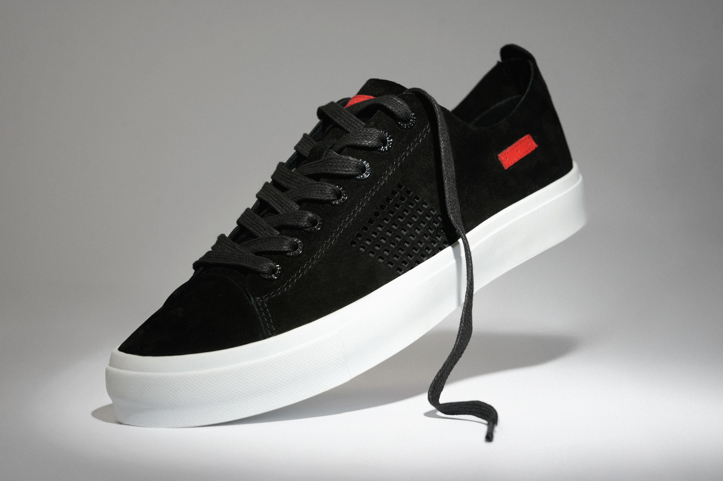 Commercial product photograph of a black sneaker with a white sole, photographed in a Los Angeles studio