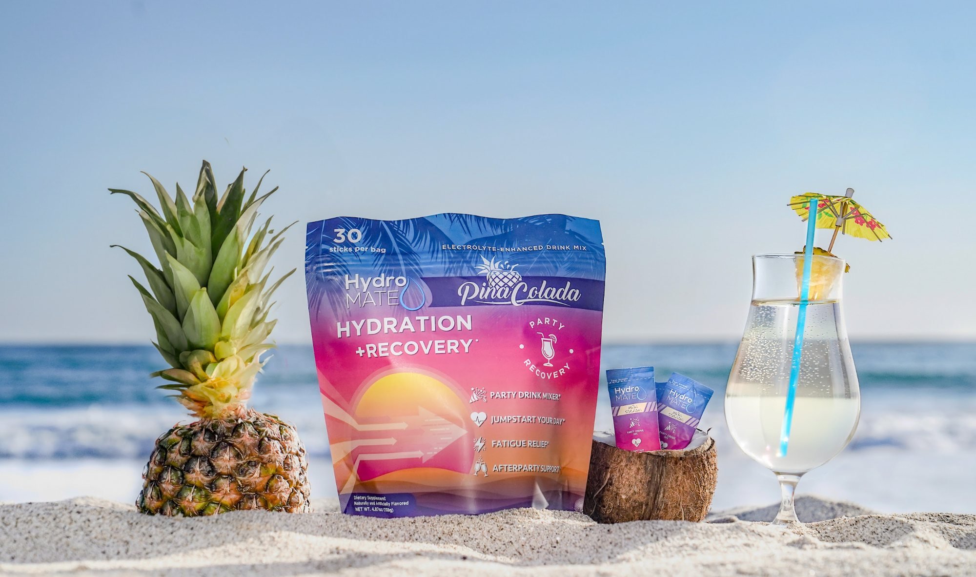 HydroMate Pina Colada hydration pouch with pineapple, coconut and a tropical drink on the beach, brand photography in San Diego