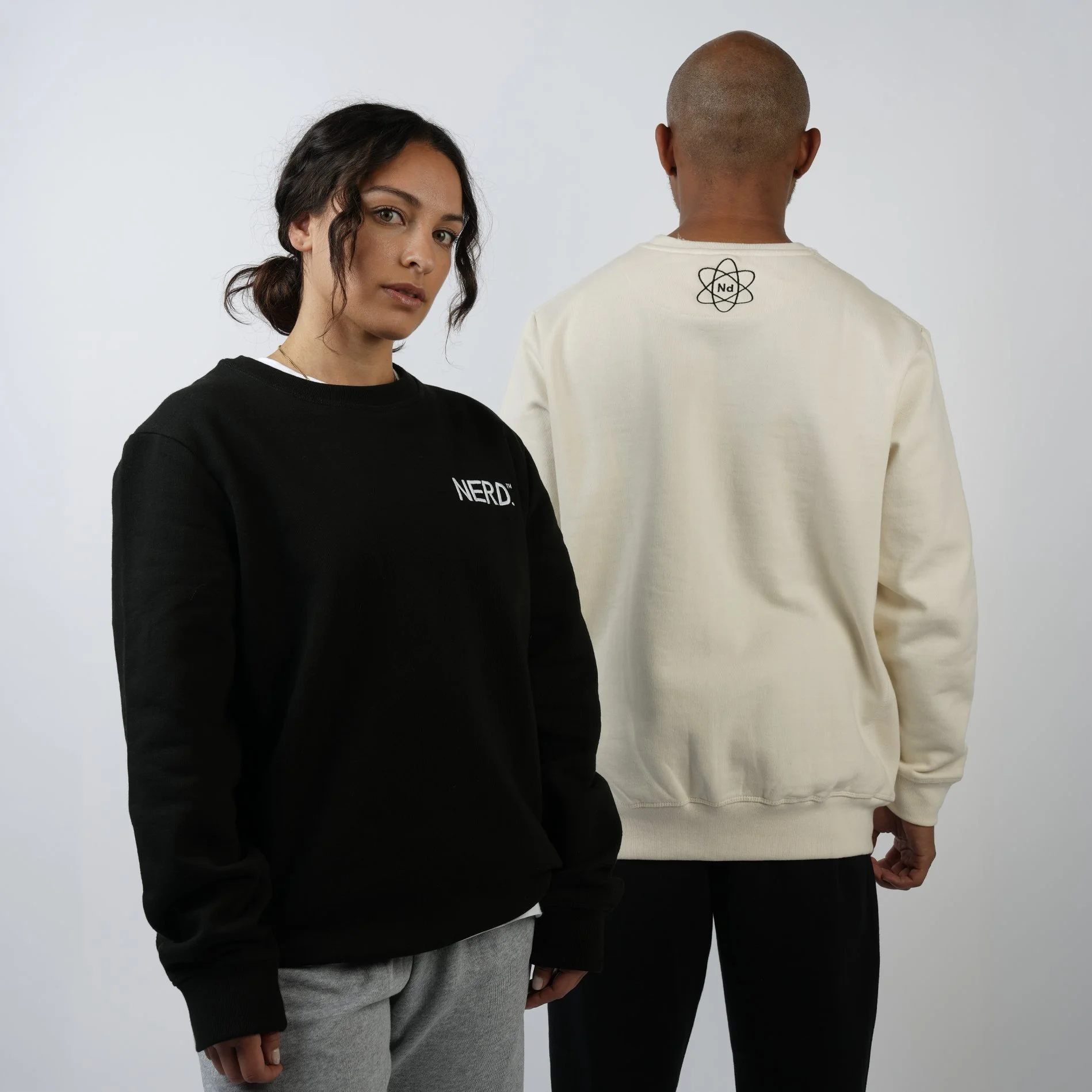 Three models on a plain backdrop, one woman facing forward and two men with their backs turned, apparel ecommerce photography