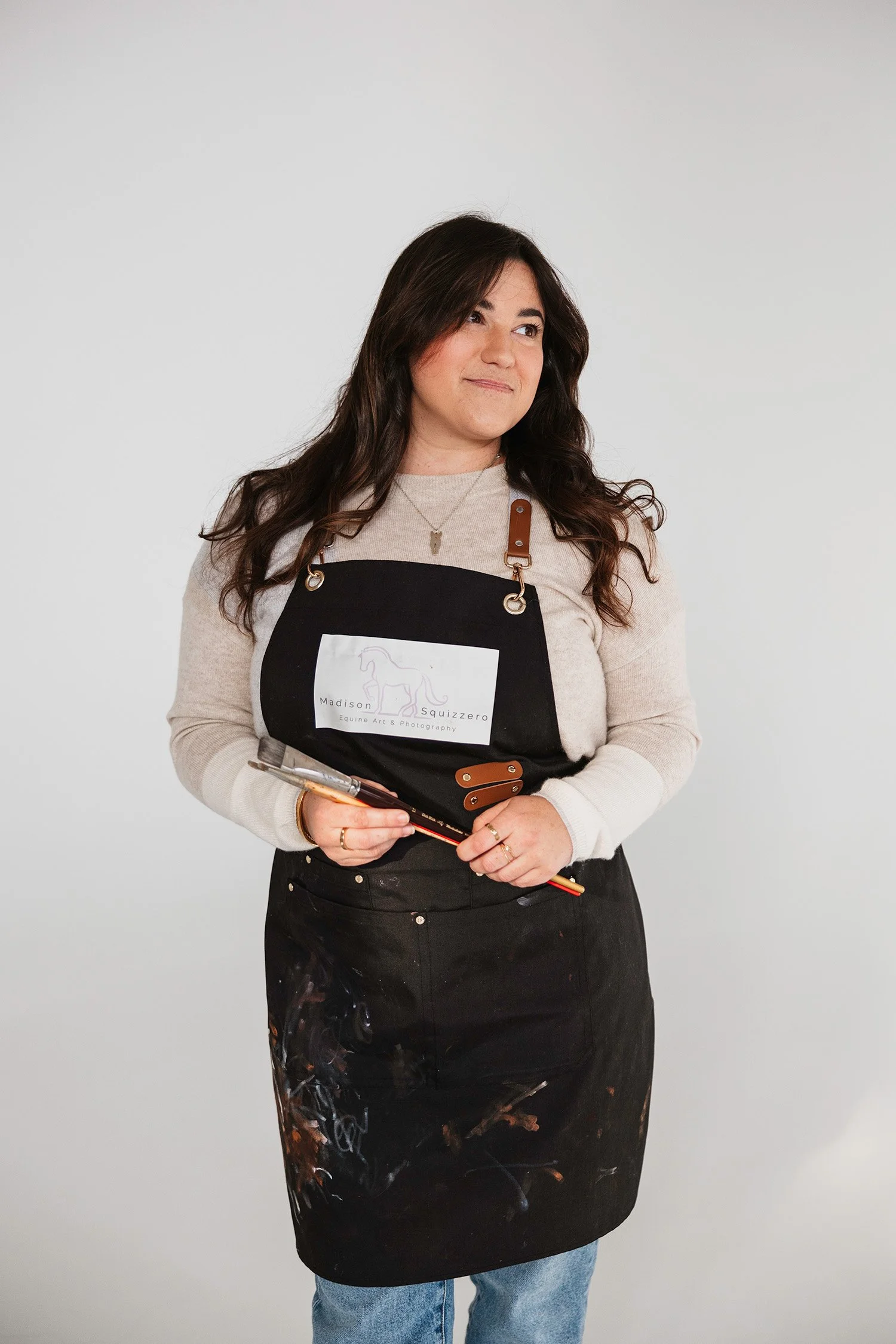 Madison Squizzero wearing an apron and holding paint brushes