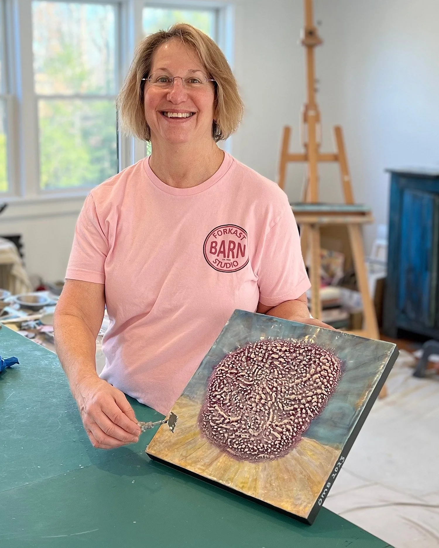 Dot Bergen in her studio holding one of her art pieces
