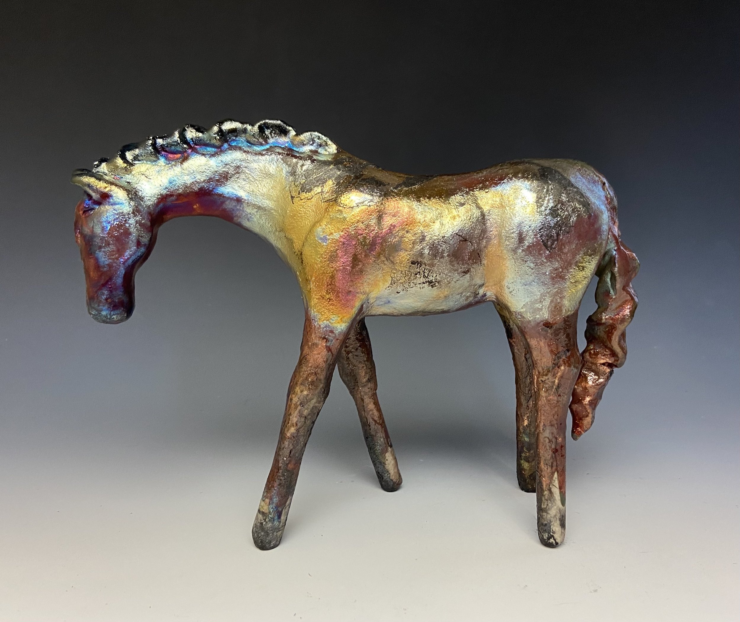  Lindsey Epstein   
 Forged by Fire   
9.5" x 11.5" 
Paper clay, porcelain This raku-fired ceramic horse emerges from fire not simply as a subject, but as a record of the element itself. The surface bears the unpredictable signatures of flame. Smoke,