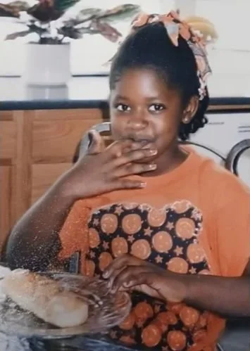 Image of Amber Creamer as a child sitting at kitchen table eating a doughnut.