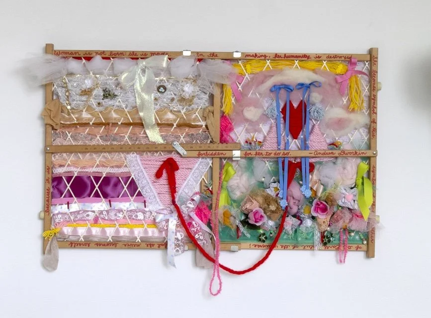 Two handcrafted shadow boxes filled with colorful ribbons, fabrics, feathers, and decorative ornaments, mounted on a wall.