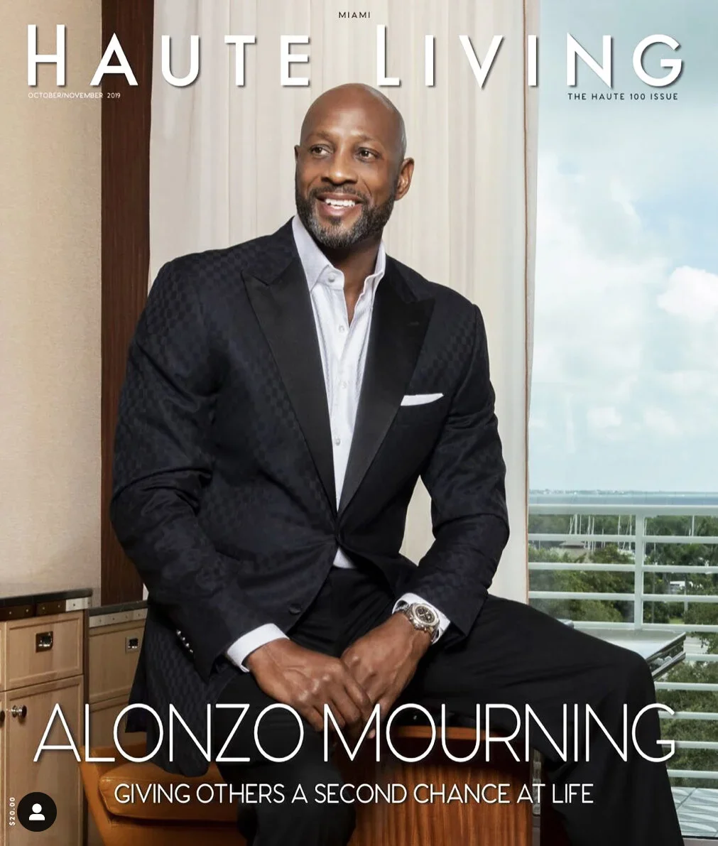 Magazine cover featuring Alonzo Mourning in a black suit with a white shirt, seated in a room with a balcony view of a cloudy sky and trees, with the title 'Haute Living' and headline about Alonzo Mourning.