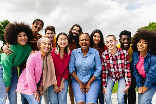 Group of diverse young adults smiling outdoors on a cloudy day.