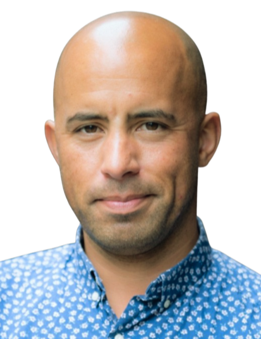 A portrait of a bald man with a slight smile, wearing a blue patterned shirt, against a plain background.