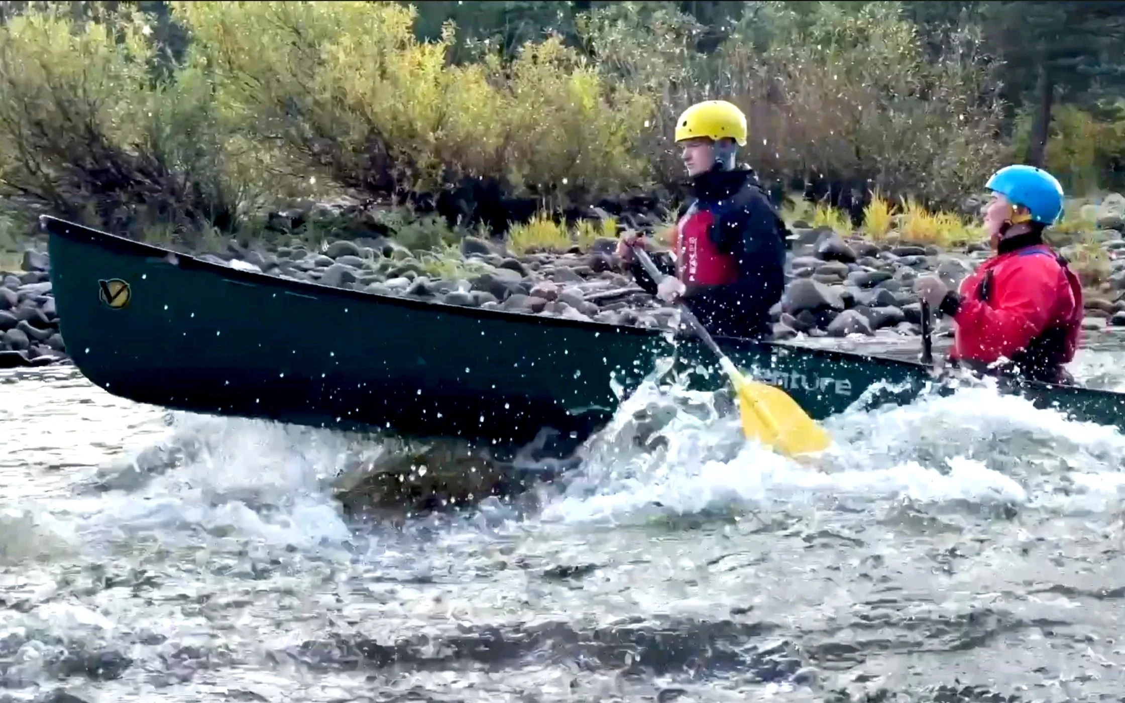 2 young people in a canoe go down rapids on the River Spey.