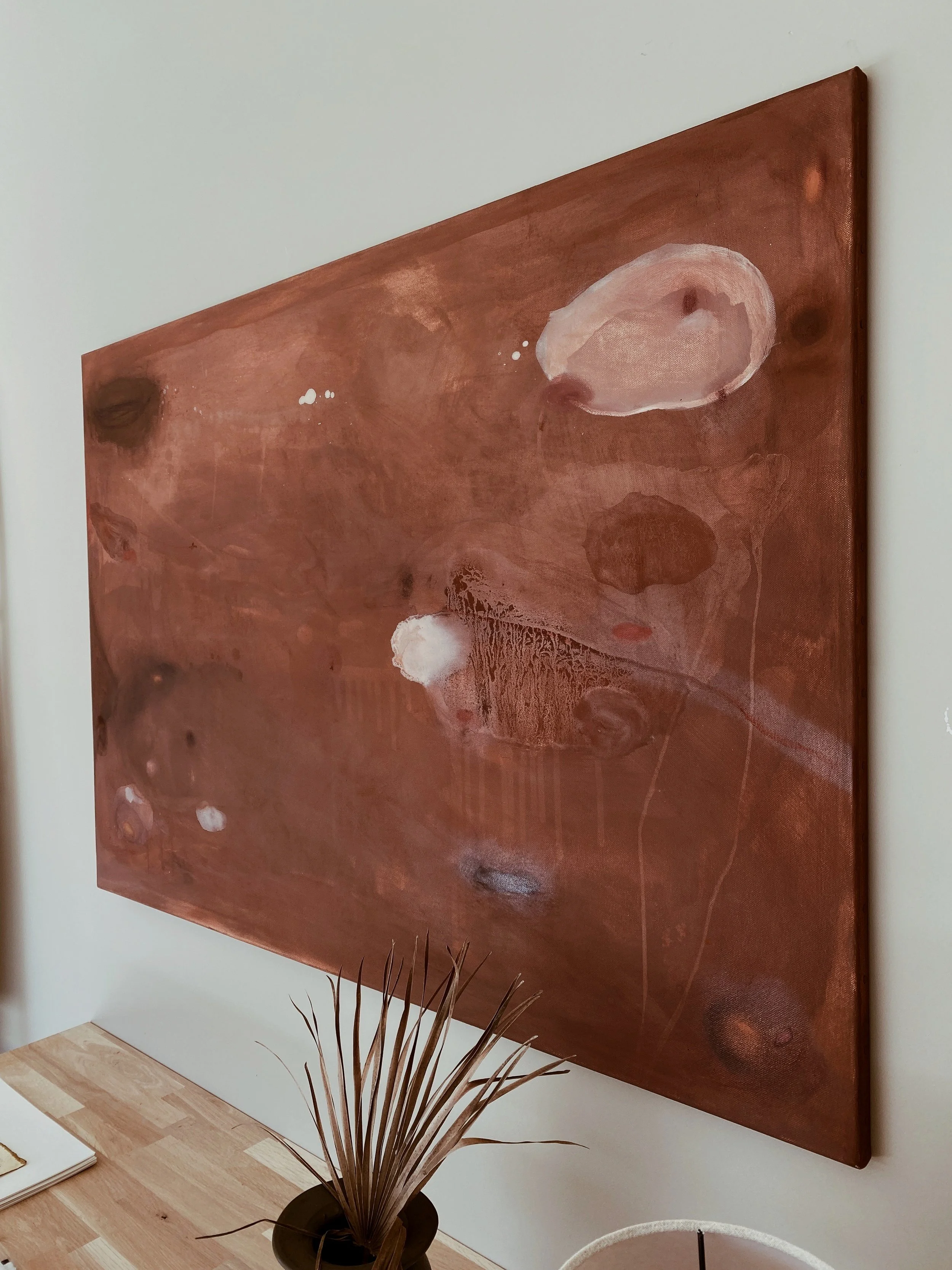Abstract painting with earthy tones, featuring various organic shapes and textures on a wooden wall.