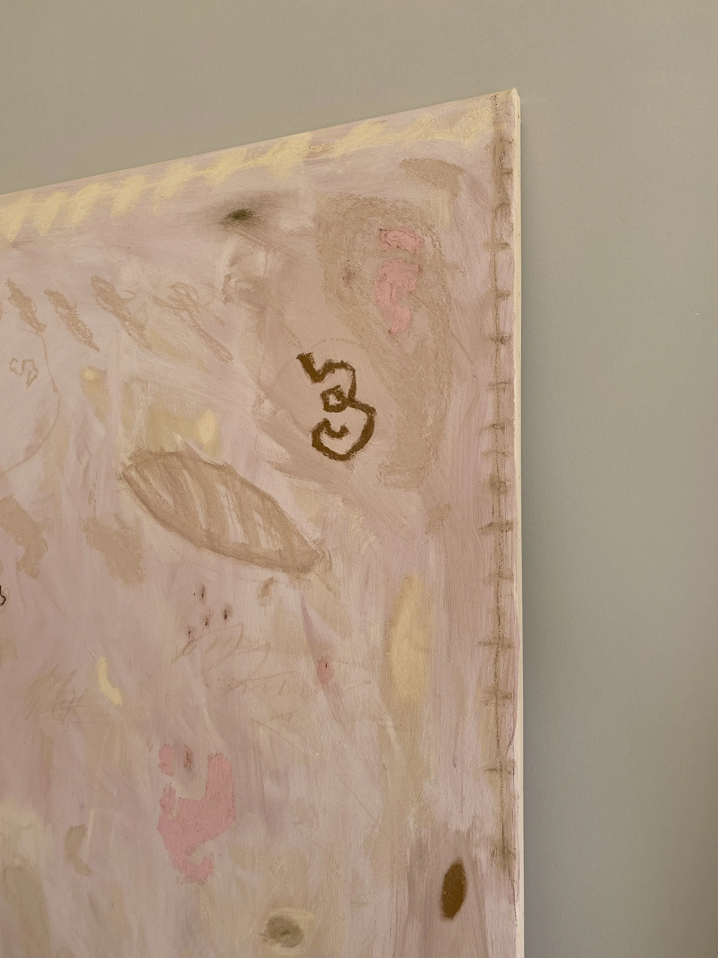 Close-up of a pastel pink and beige abstract artwork with black and brown marks, and visible canvas texture, on a wall.