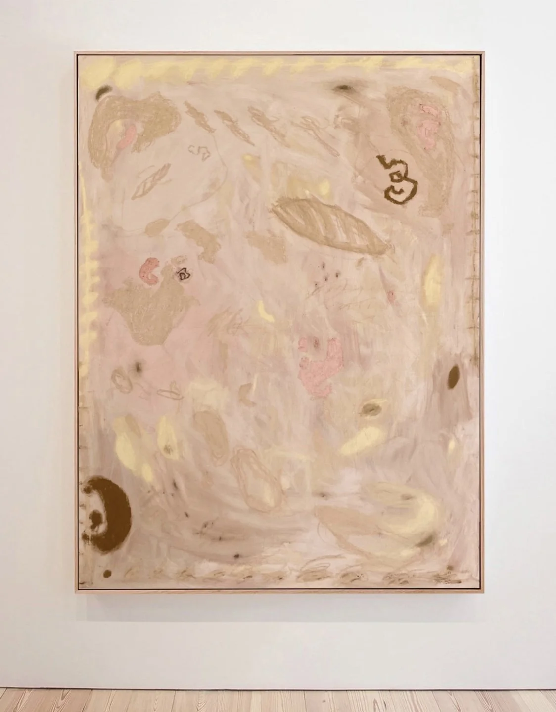 Abstract painting with soft pink, beige, and yellow swirls and scattered darker accents on a white gallery wall.