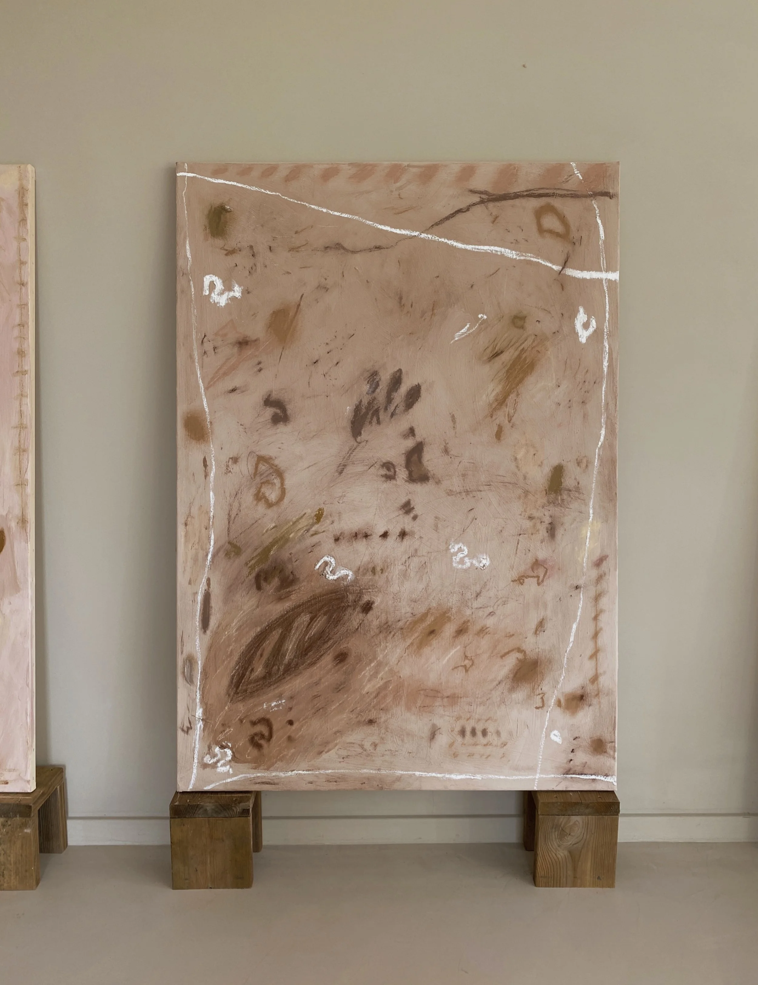 Abstract painting with brown, pink, and white hues, featuring faint markings, lines, and data points, displayed on a wall with wooden supports.