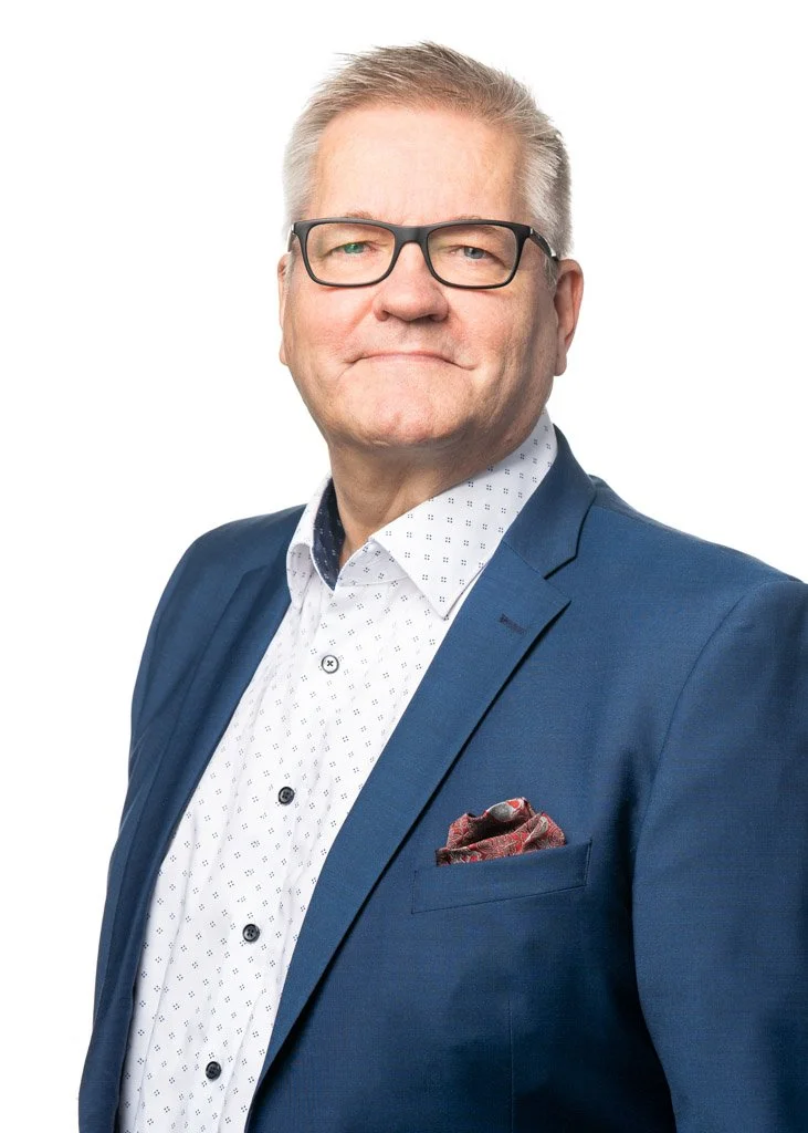 Mies sinisessä bleiserissä, kuviollinen taskuliina rintataskussa