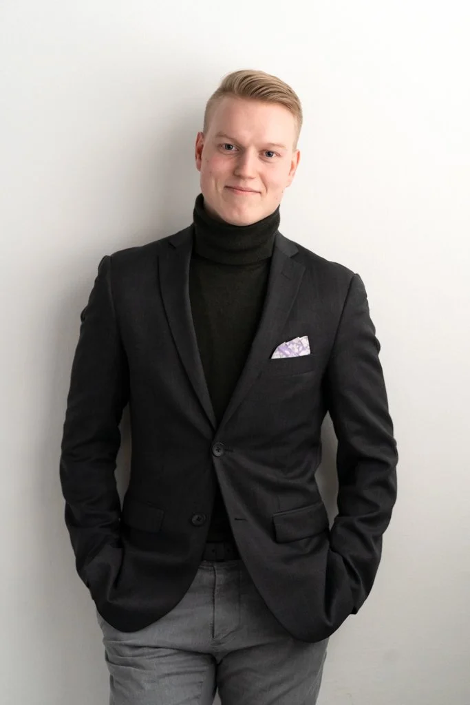 Nuori mies tummassa bleiserissä ja oliivinvihreässä poolopaidassa