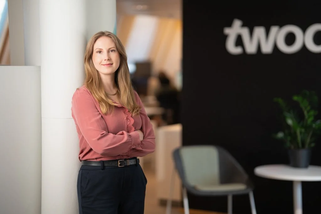 twodayn työntekijä toimiston aulassa, yrityksen logo taustalla