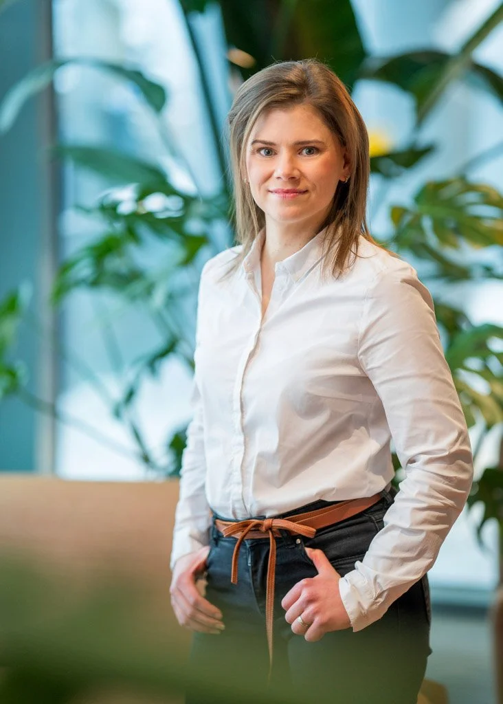 Nainen valkoisessa kauluspaidassa toimistossa, viherkasvit taustalla