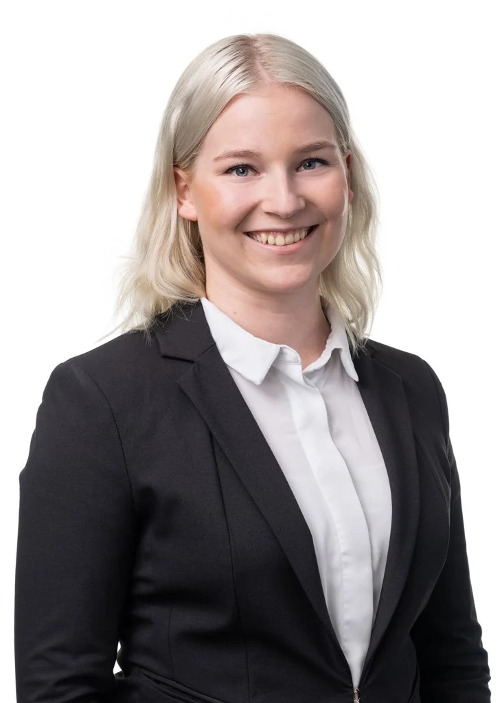 Erika Ahlberg mustassa tunikassa nojaa vaaleaan seinään