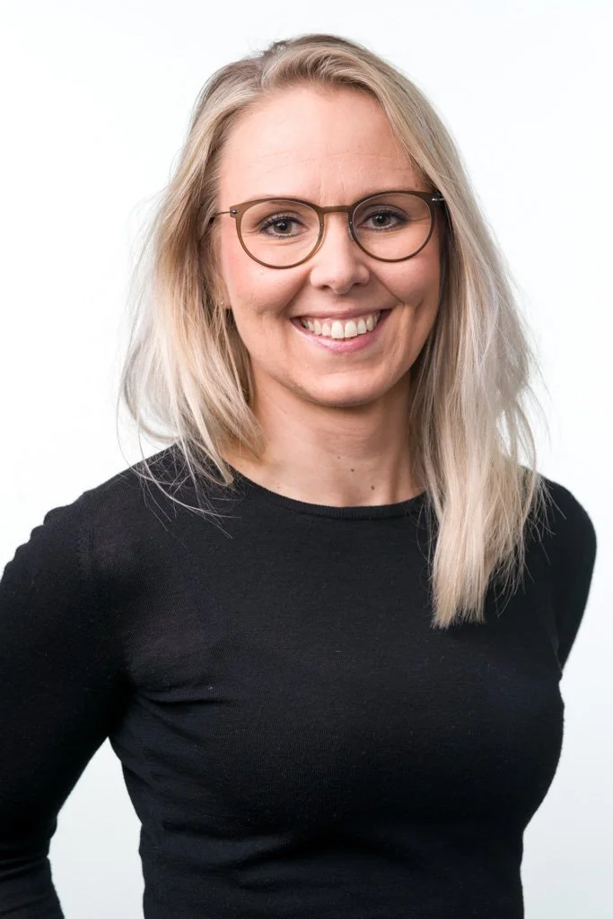 Vaaleahiuksinen nainen silmälaseissa ja mustassa paidassa, valkoinen tausta