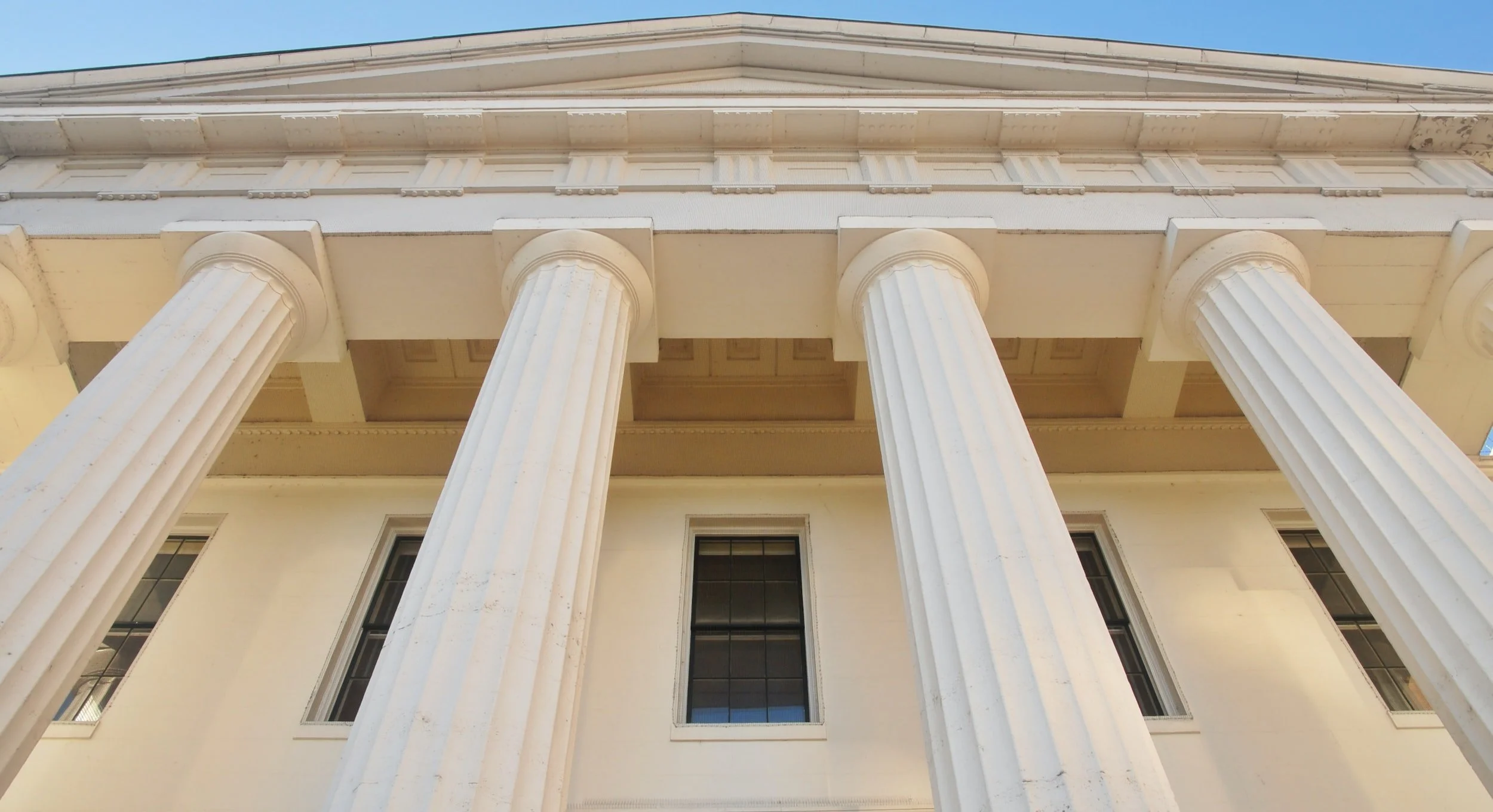 The outside of a courthouse with 4 columns.