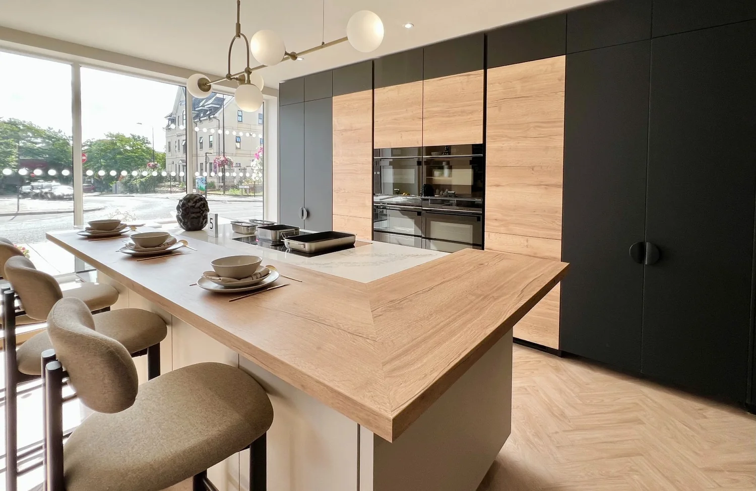 The German handleless display at our Aylesbury showroom: dark matt doors, warm oak tall units and a breakfast island