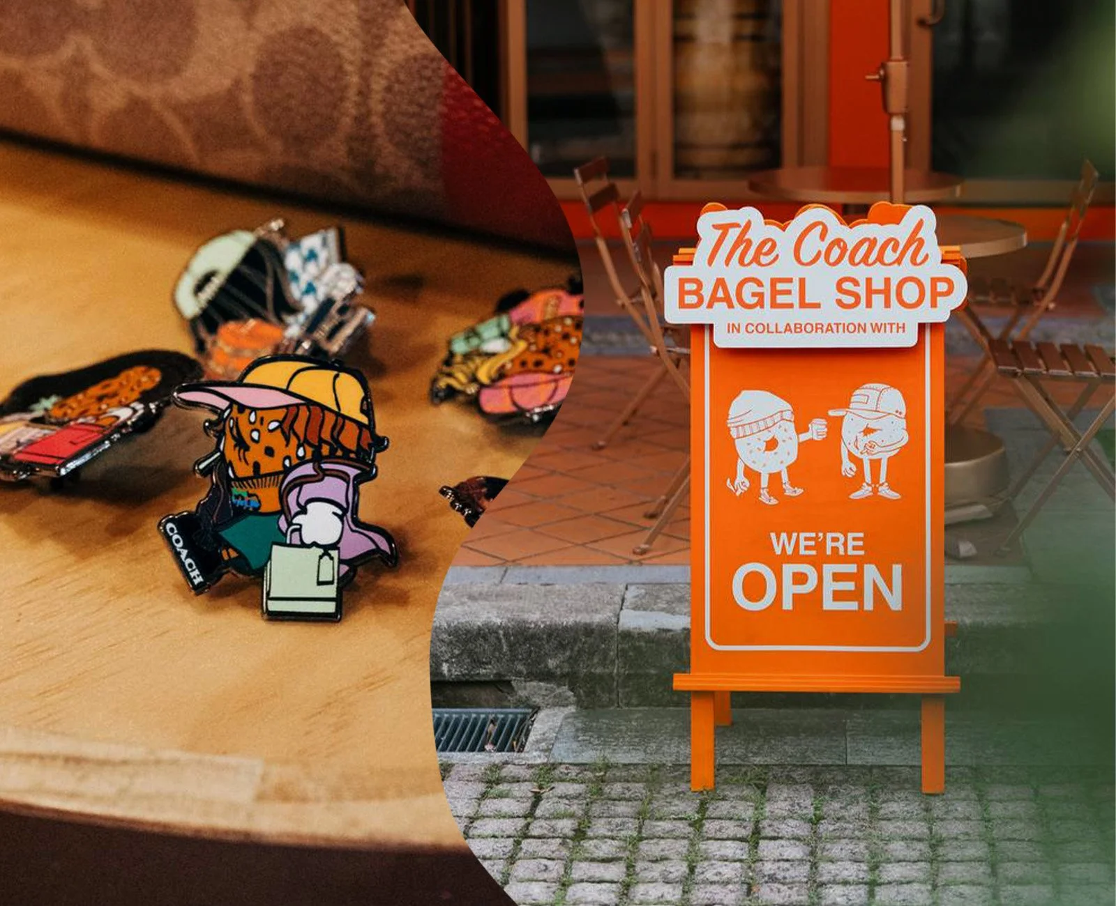 A close-up of colorful enamel pins on a wooden table, with a shop window and outdoor patio furniture in the background, and an orange sign outside the shop that reads 'The Coach Bagel Shop in Collaboration With We're Open' featuring illustrations of 