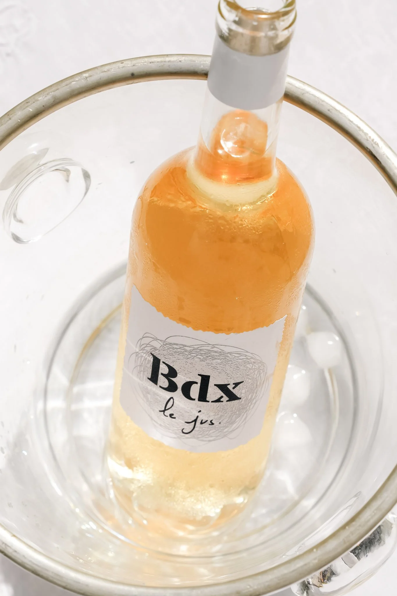 Bouteille de jus de couleur orange claire dans un seau en métal avec une étiquette "Ibdx le jus"