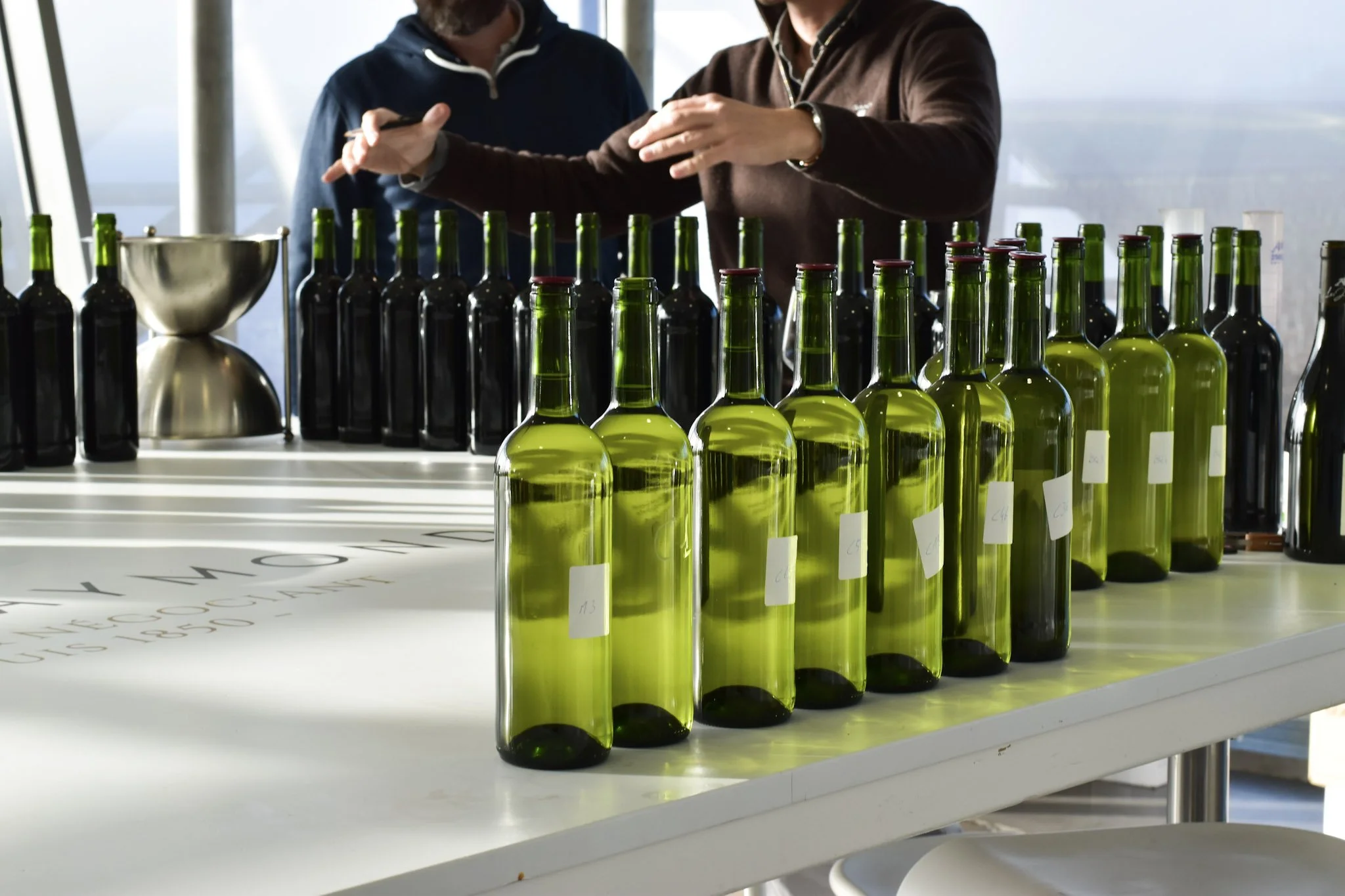 Ligne de bouteilles de vin ou d'huile sur une table lors d'une dégustation ou d'une fabrication.