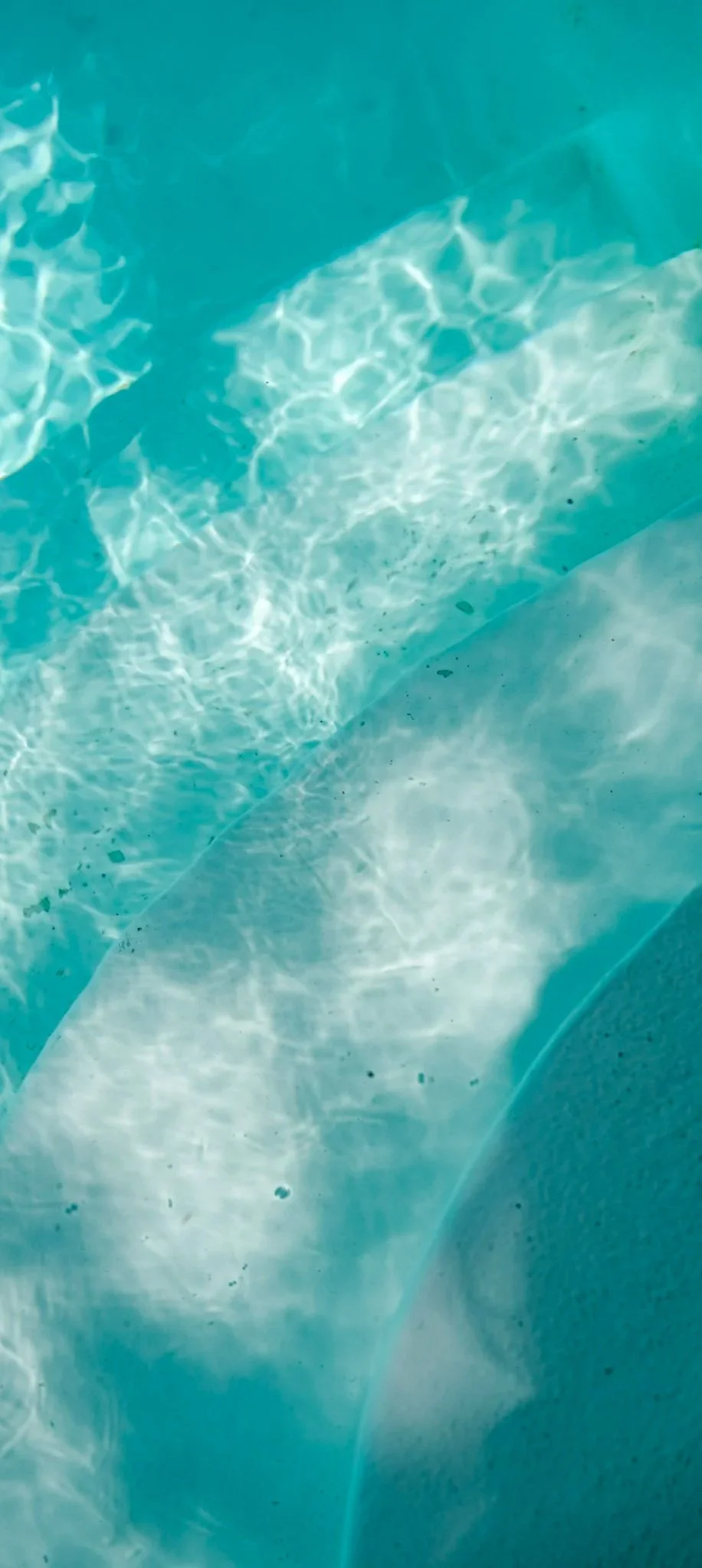 Eau claire dans une piscine avec reflets lumineux et une surface légèrement ondulée.