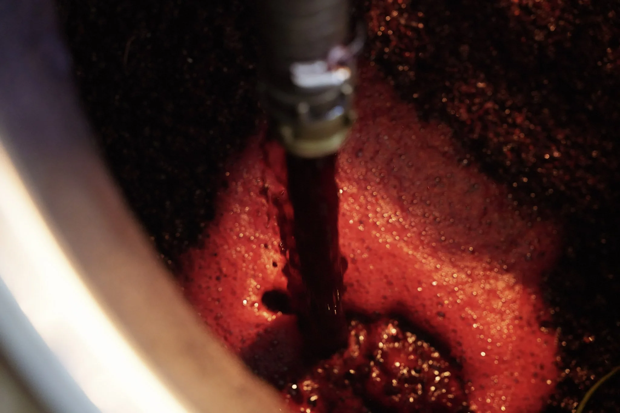 Vitesse d'eau foncée coulant dans une machine à espresso, avec une mousse rougeâtre visible autour.