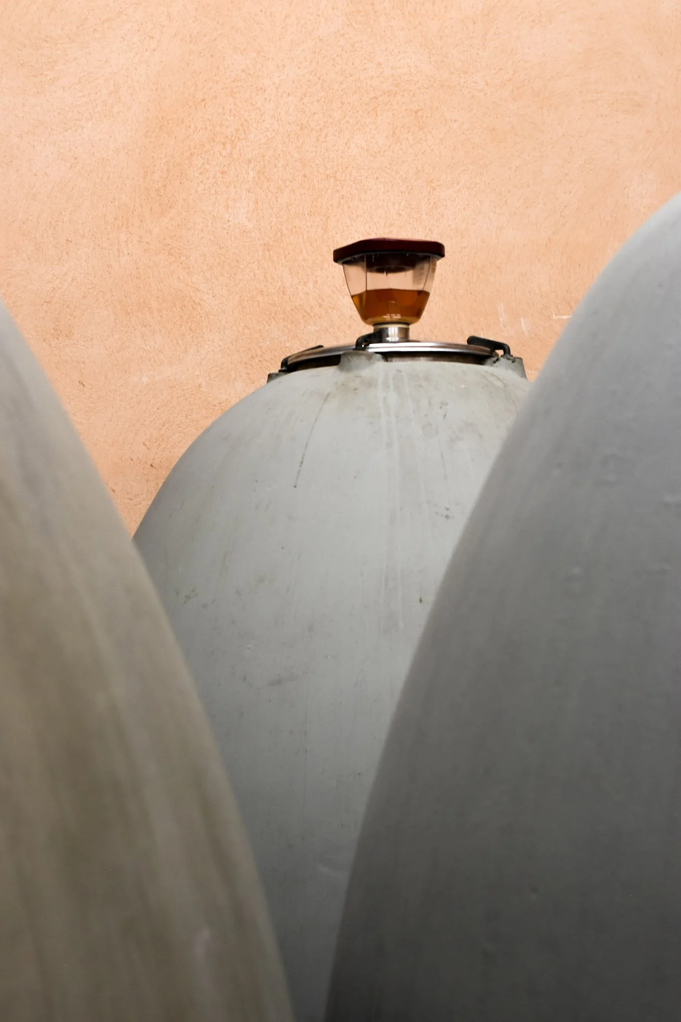 Vue en contre-plongée d'une cheminée ou d'une structure métallique sur un toit, avec un fond de mur en plâtre rose.