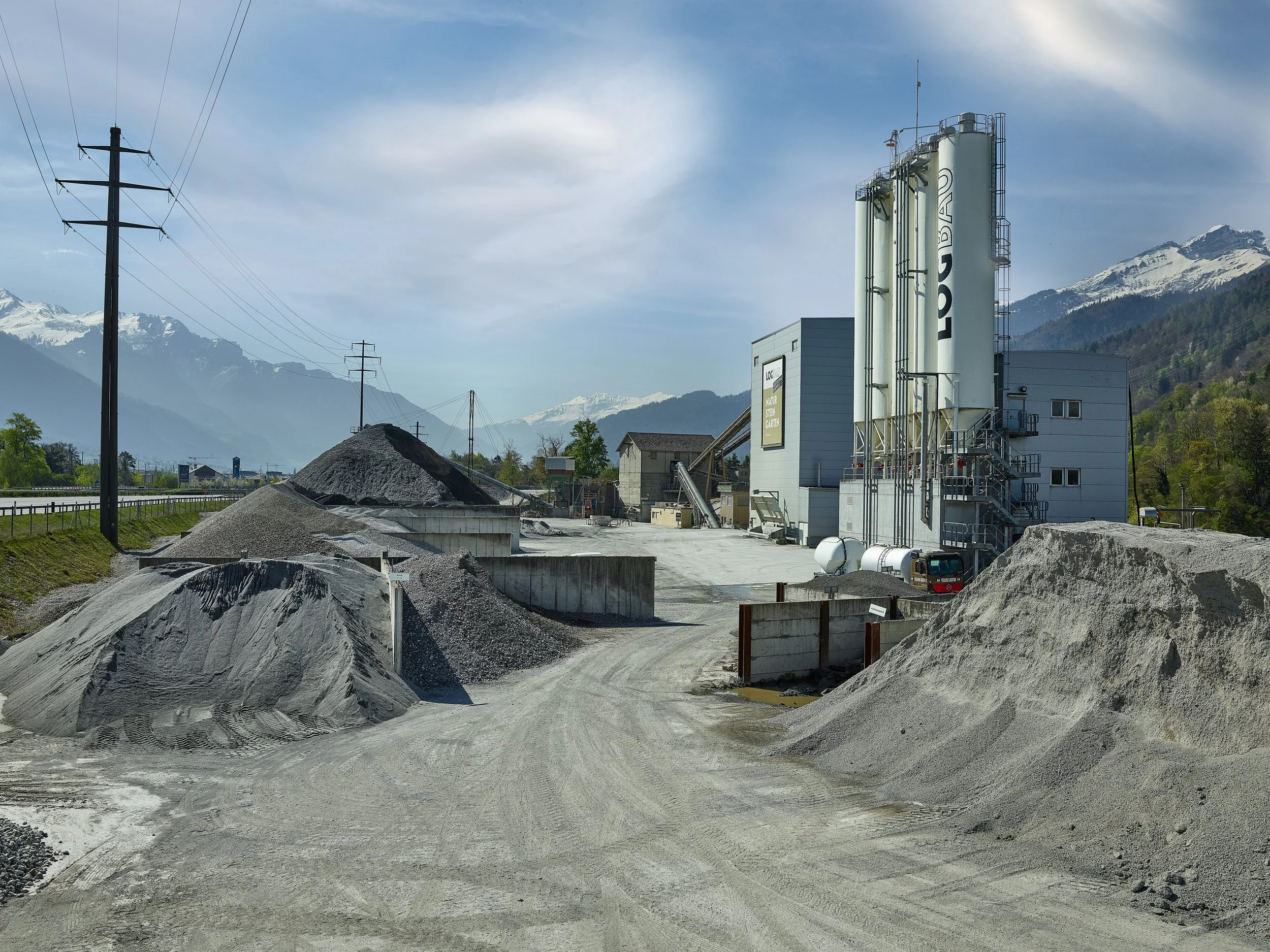 Betonanlage in einem industriellen Gebiet mit Bergen im Hintergrund.