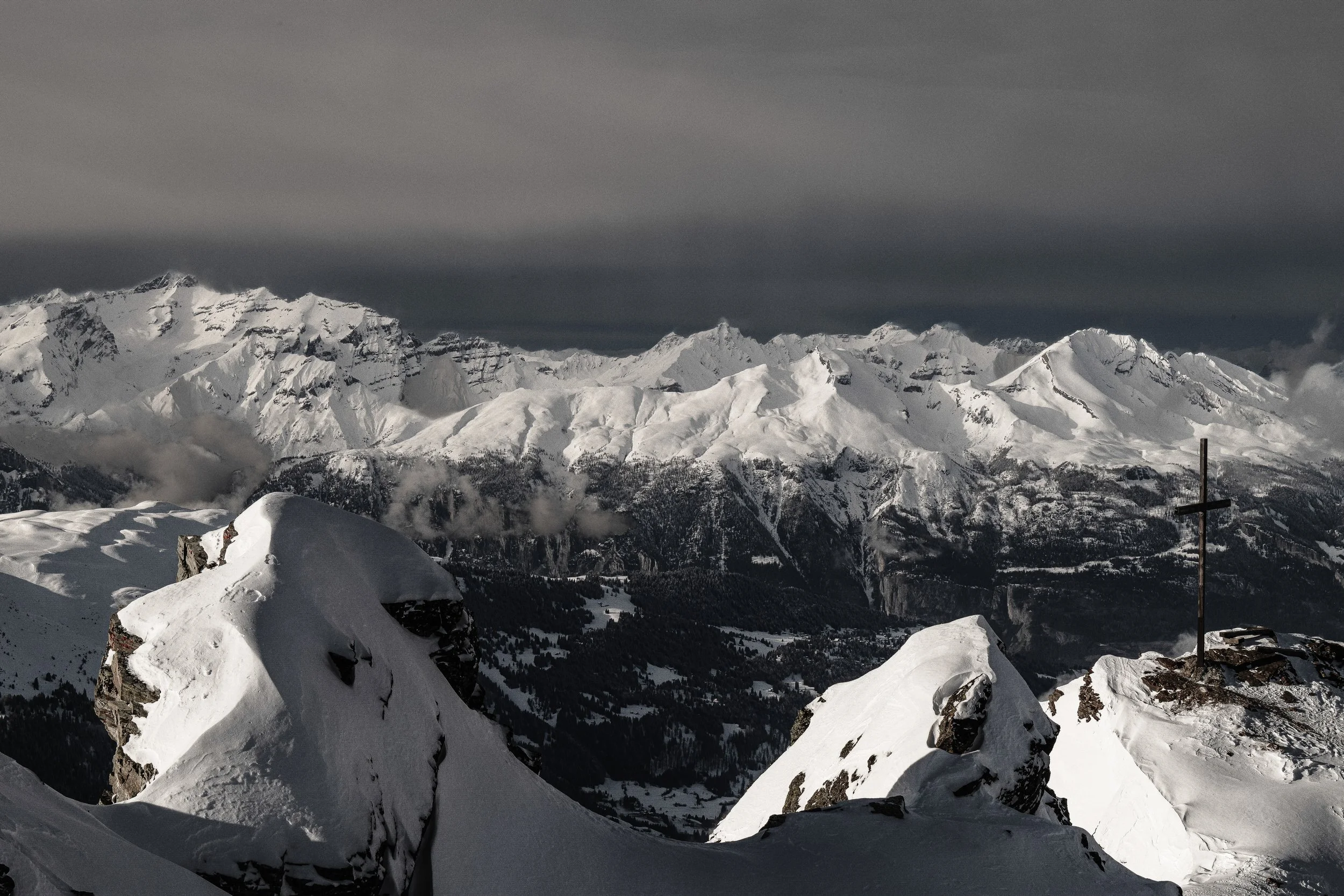 Schneebedeckte Berge und Felsen in einer winterlichen Berglandschaft unter dunklen Wolken
