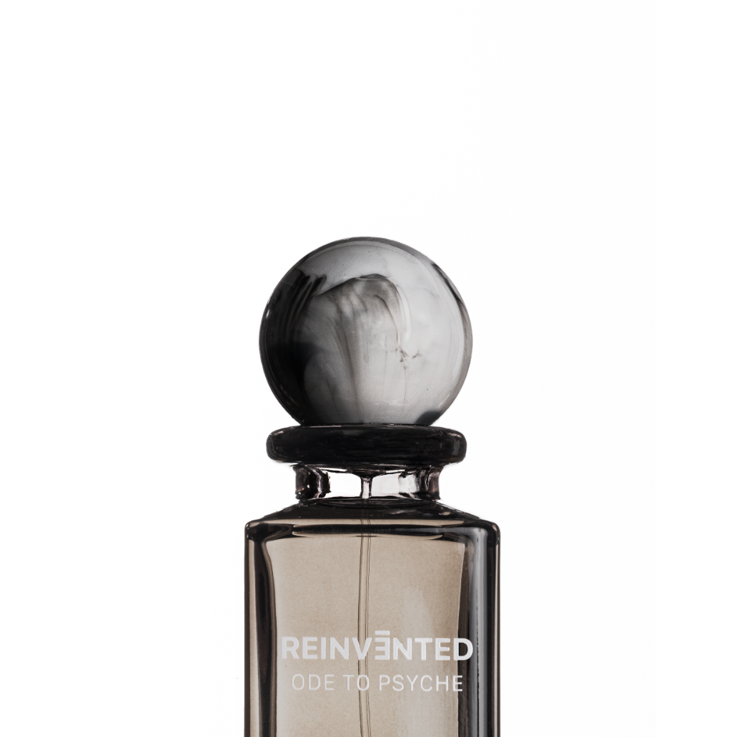 Parfümflasche mit schwarzem und weißen Design, Etikett mit der Aufschrift 'REINVENTED ODE TO PSYCHE' auf weißem Hintergrund.